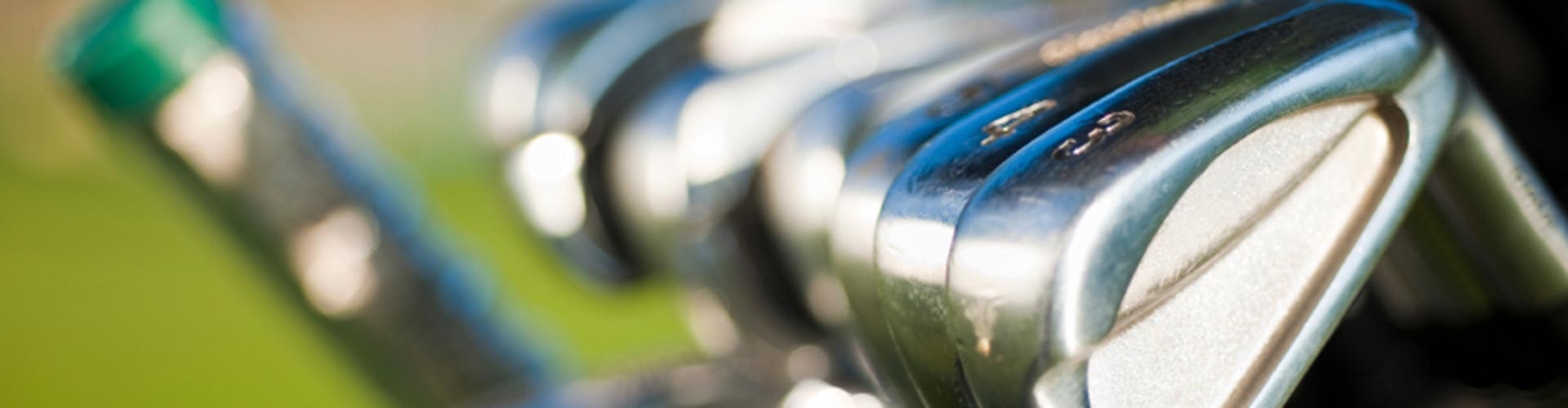 Golfklubbor med en golfbana i bakgrunden