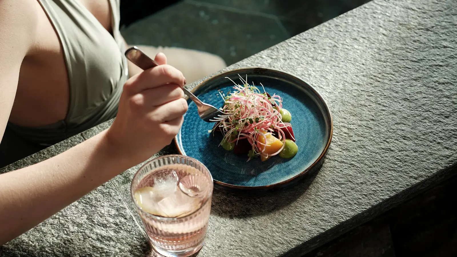 Woman eating and drinking lying in a pool