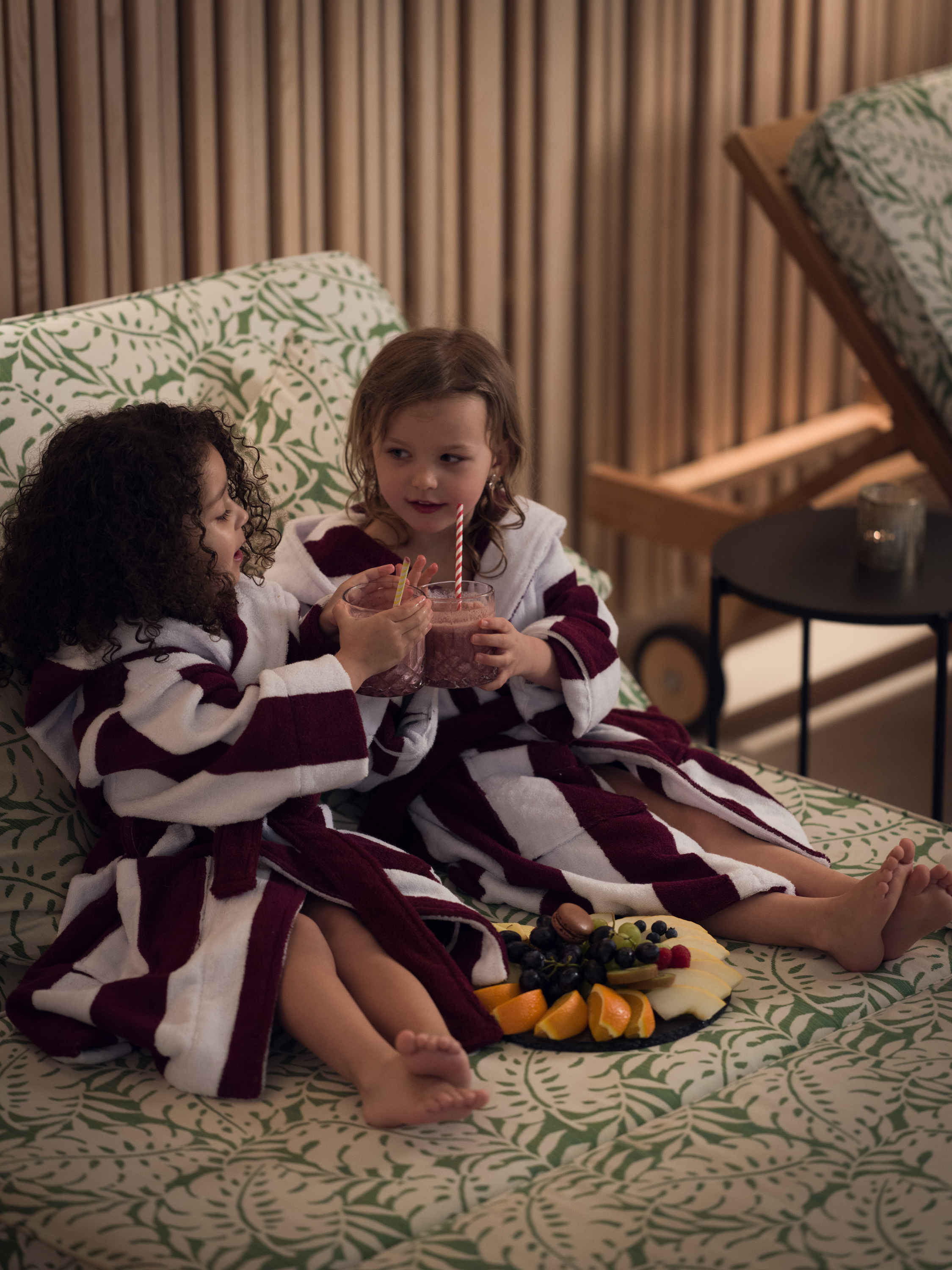 Två flickor i morgonrock som skålar i en solstol