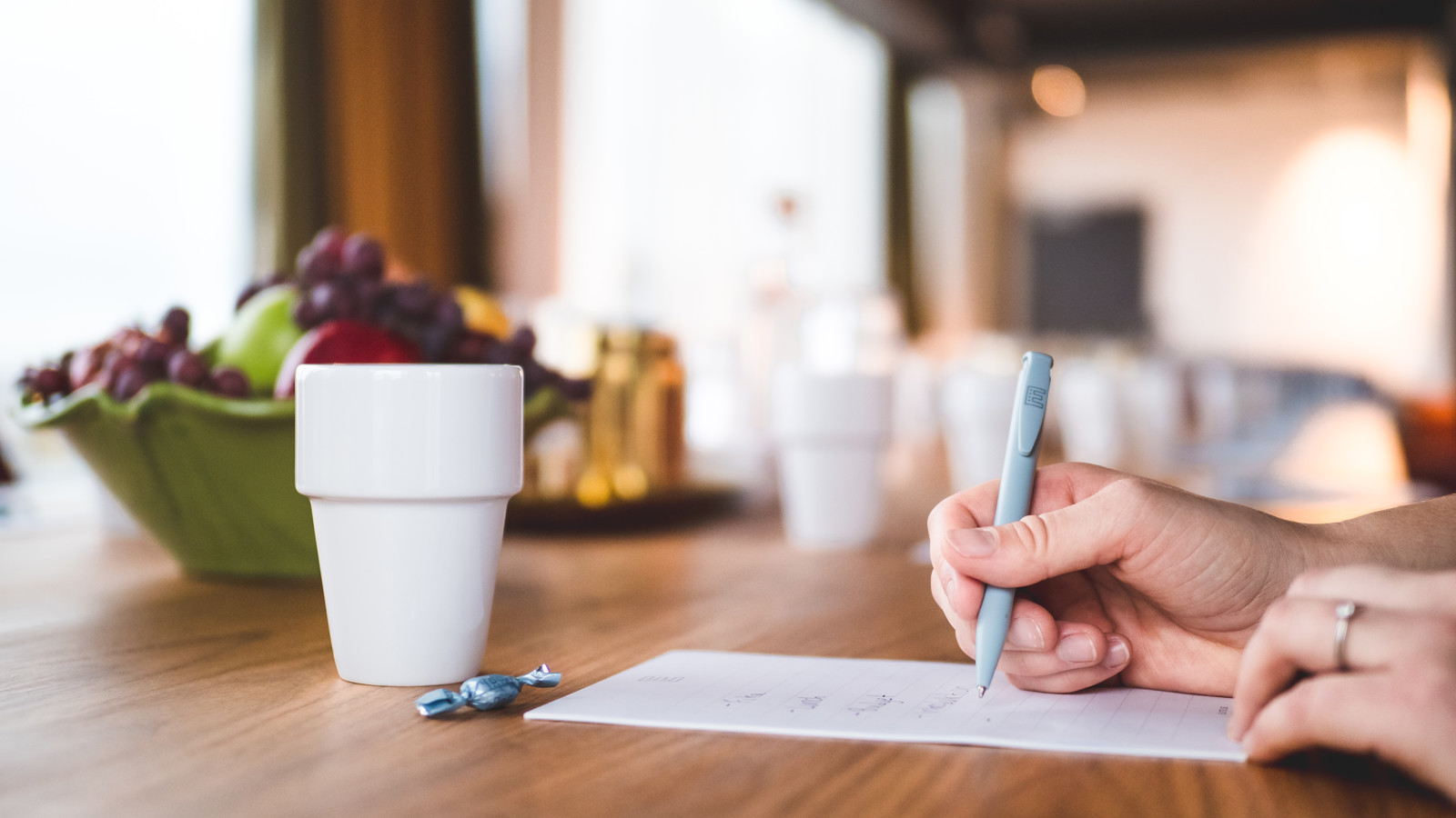 Kvinna skriver i ett konferensblock med en kopp kaffe framför sig