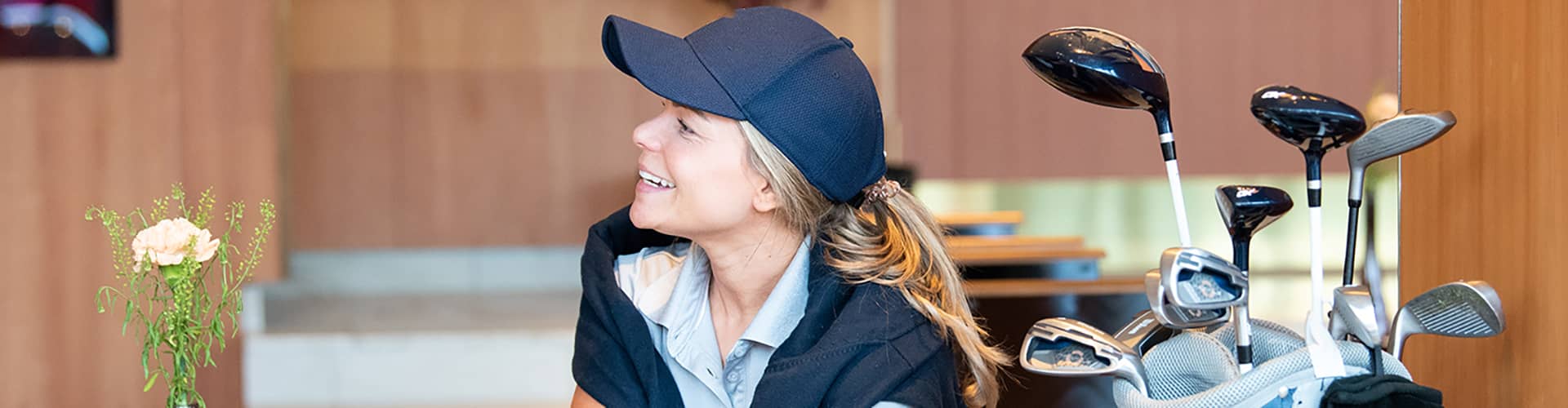 En glad tjej som sitter med en golfbag bredvid sig