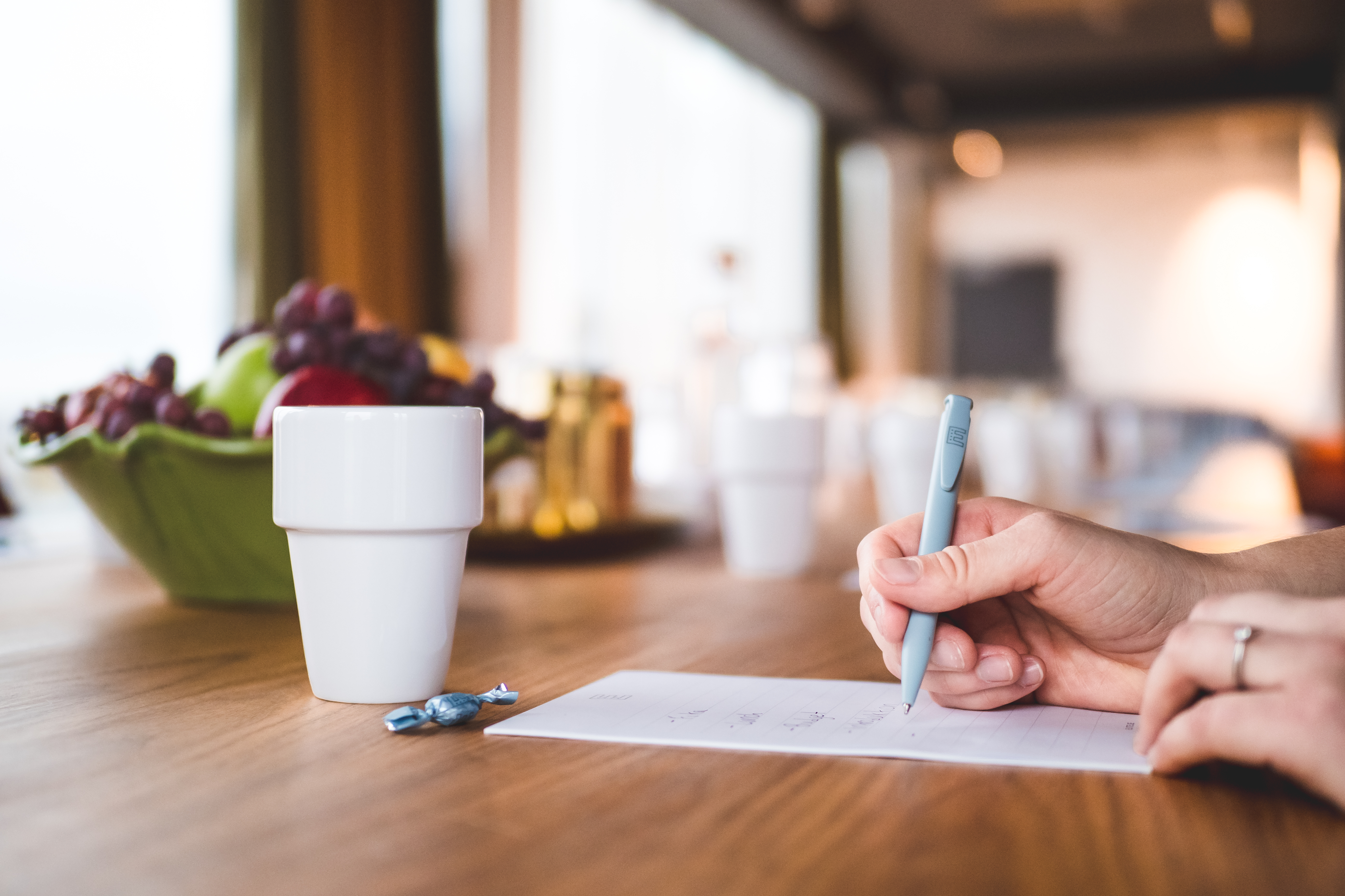 Kvinna skriver i ett konferensblock med en kopp kaffe framför sig