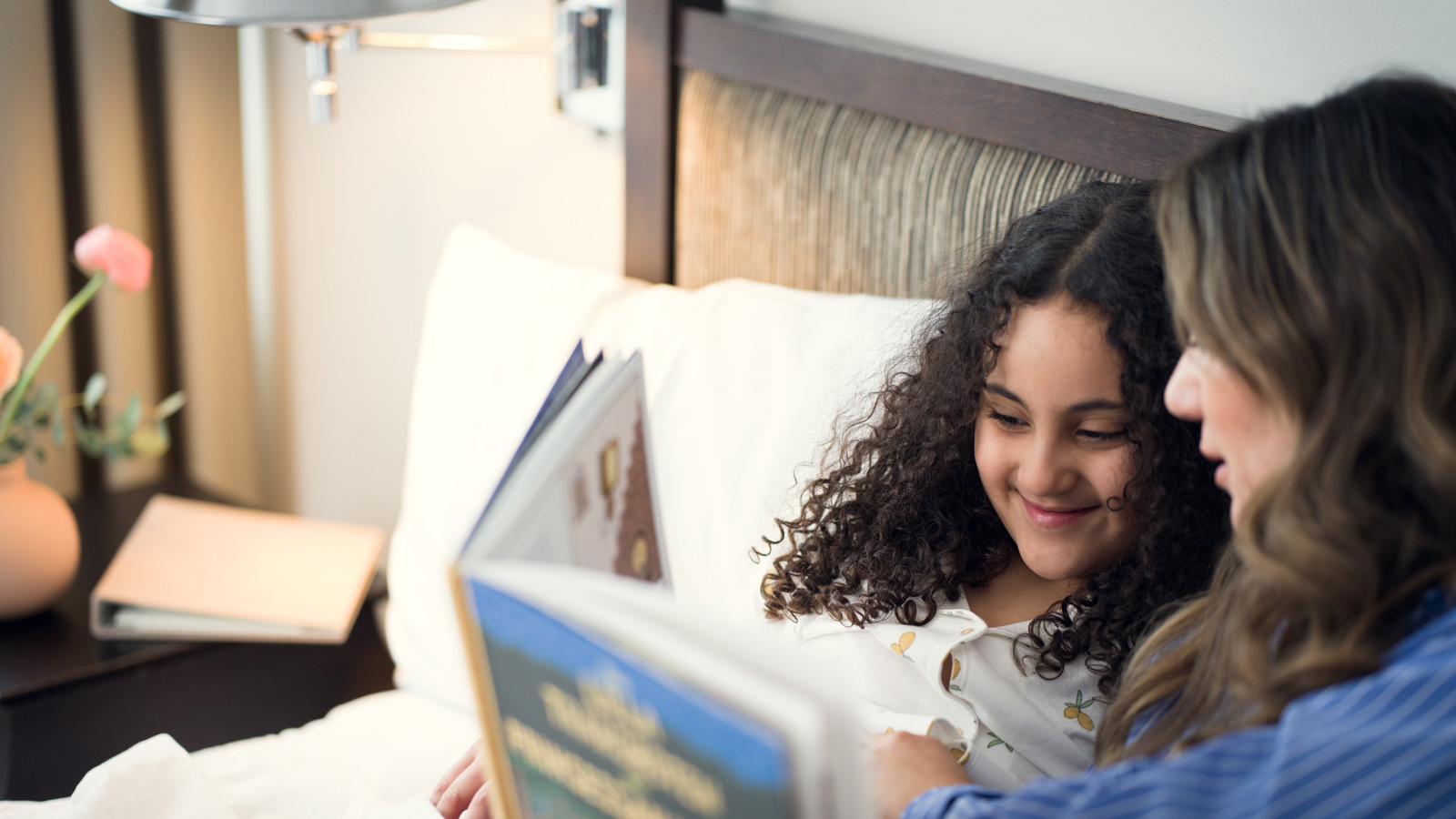 A family together on a hotel bed reading a book