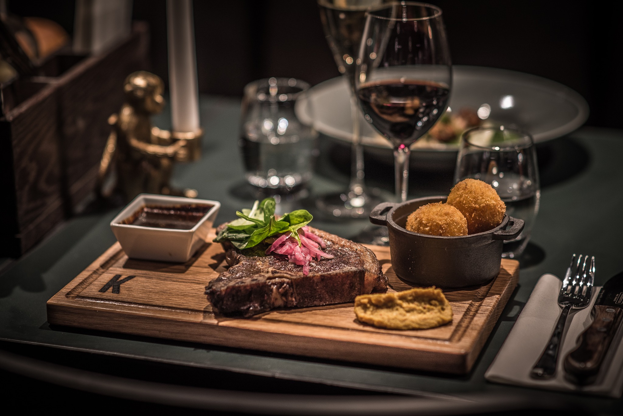Exclusive dinner with roast and sauce on a wooden platter, served with wine and accompaniments