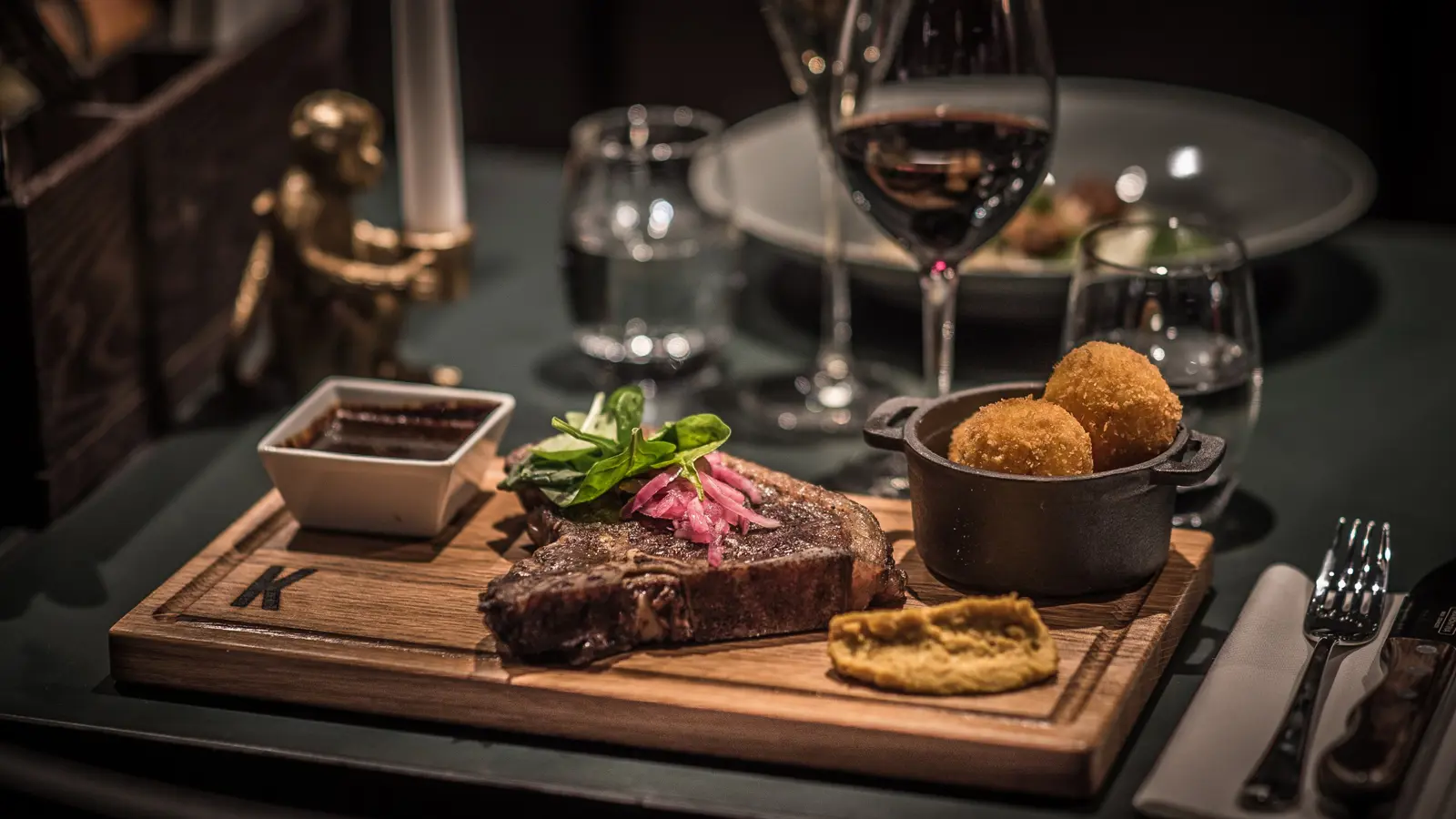 Exklusiv middag med stek och sås på träbricka, serverad med vin och tillbehör
