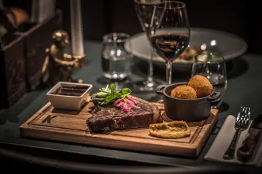 Exklusiv middag med stek och sås på träbricka, serverad med vin och tillbehör