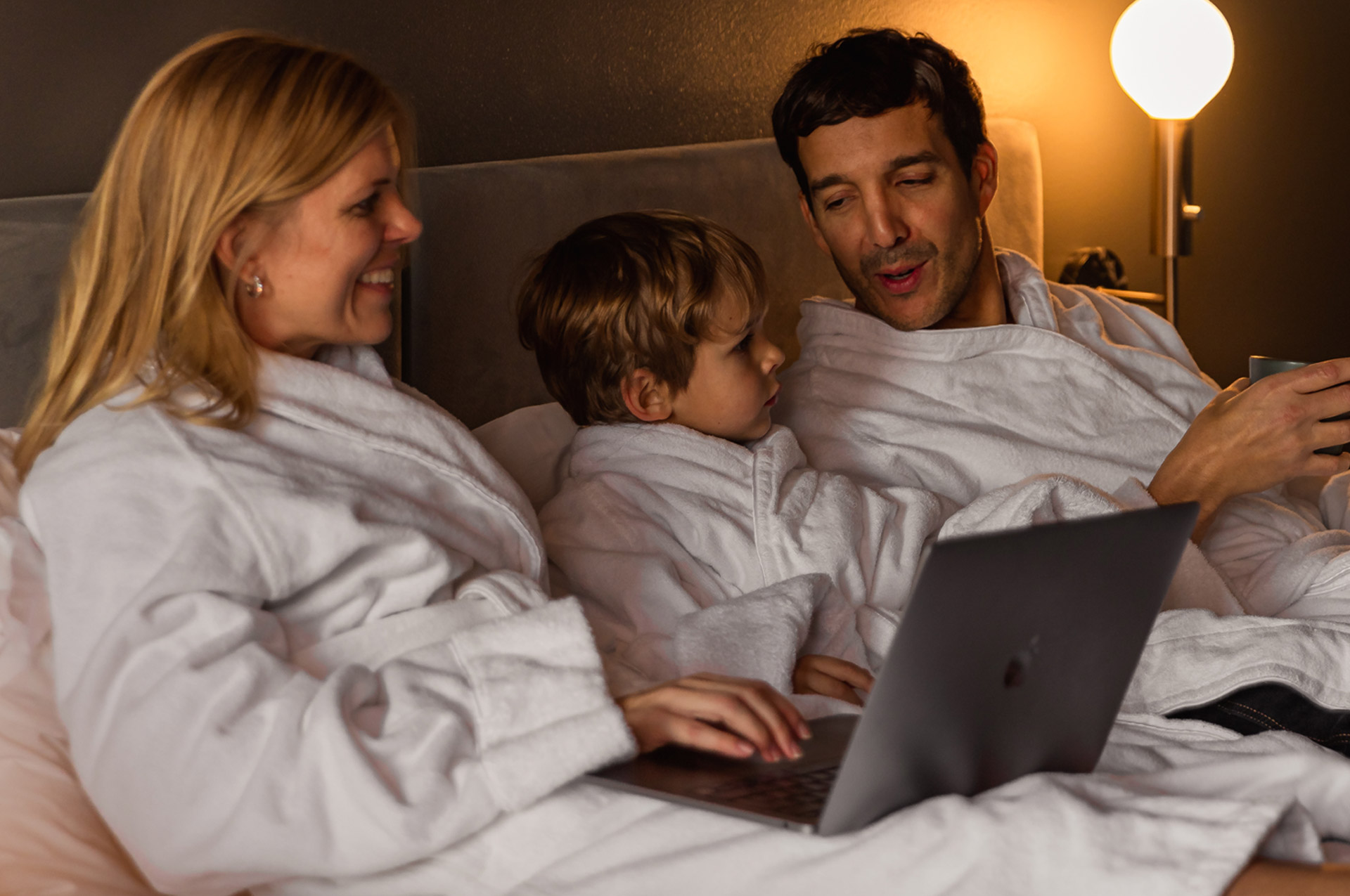 Laughing family in hotel bed at Elite Stadshotellet in Luleå