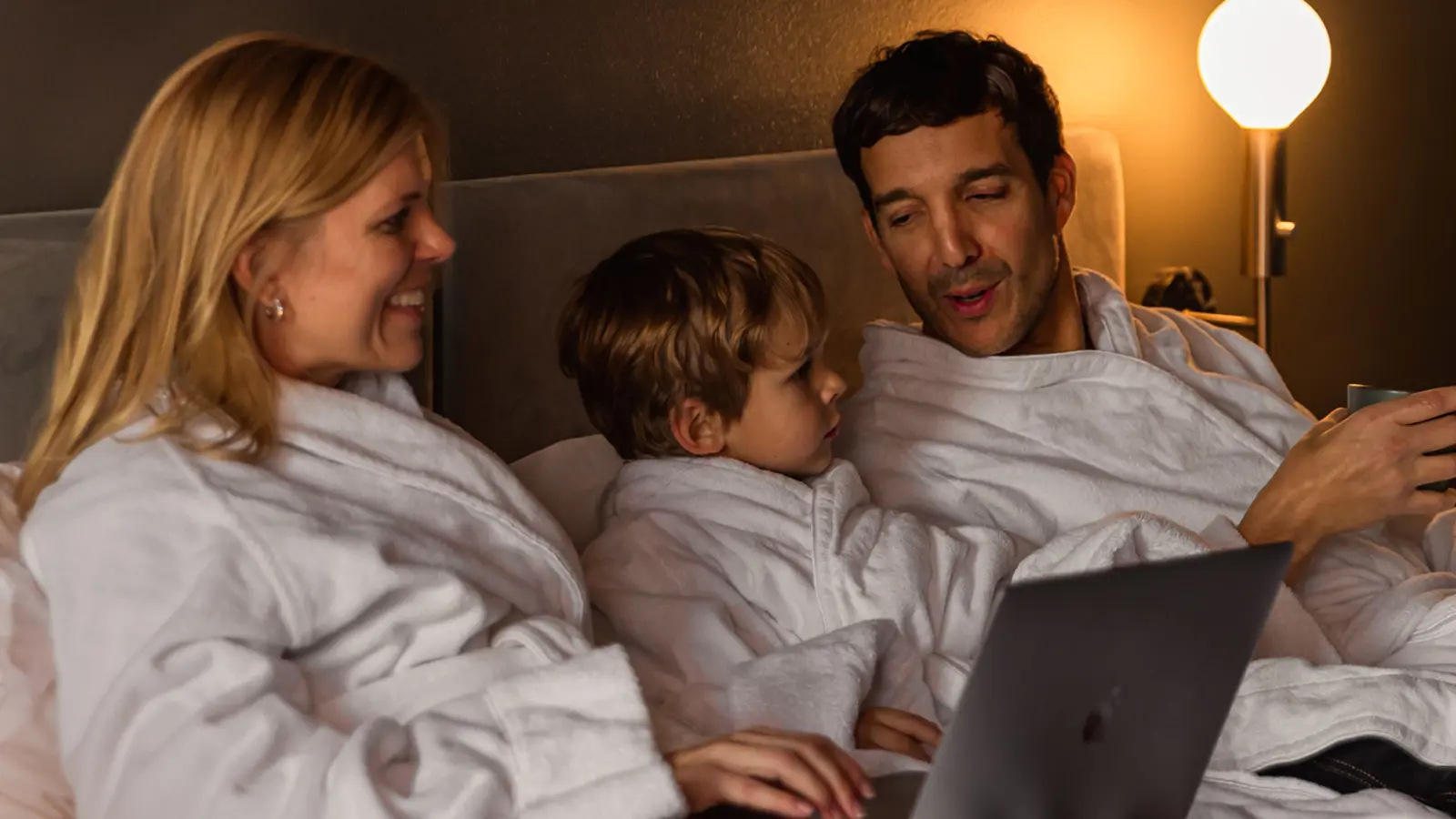 Laughing family in hotel bed at Elite Stadshotellet in Luleå