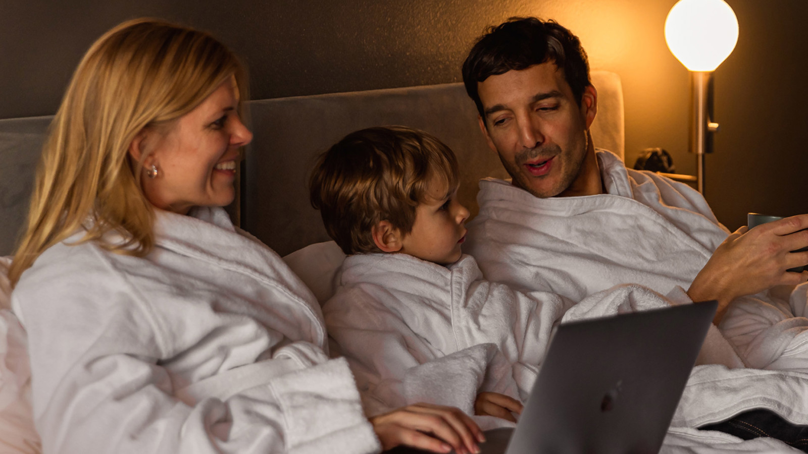 Laughing family in hotel bed at Elite Stadshotellet in Luleå