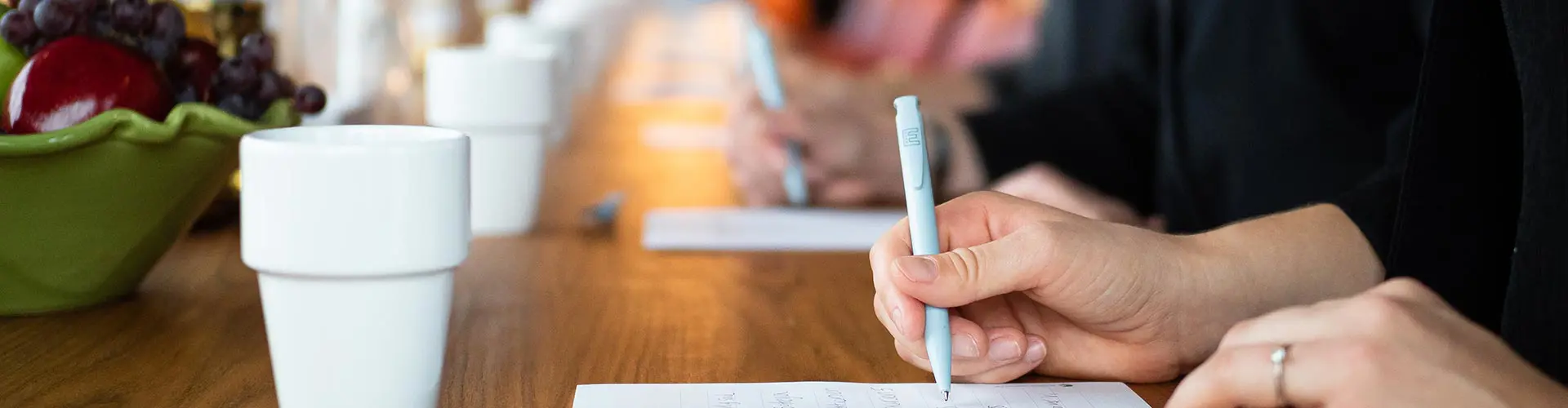 Personer antecknar på papper med kaffekoppar framför sig