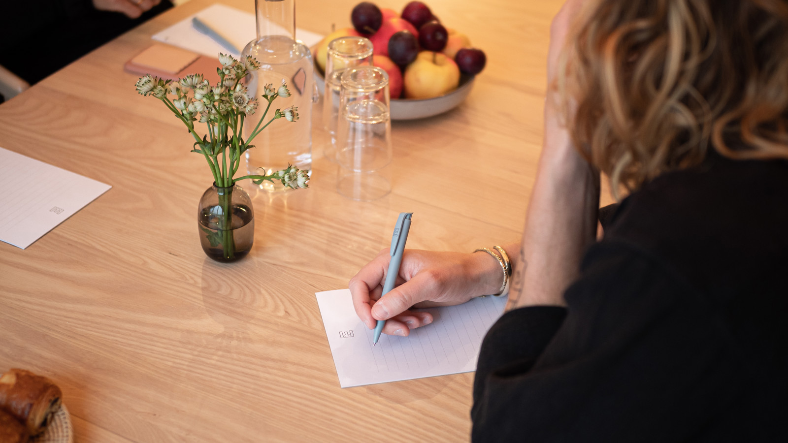 Woman writing on a paper sitting at a conference table
