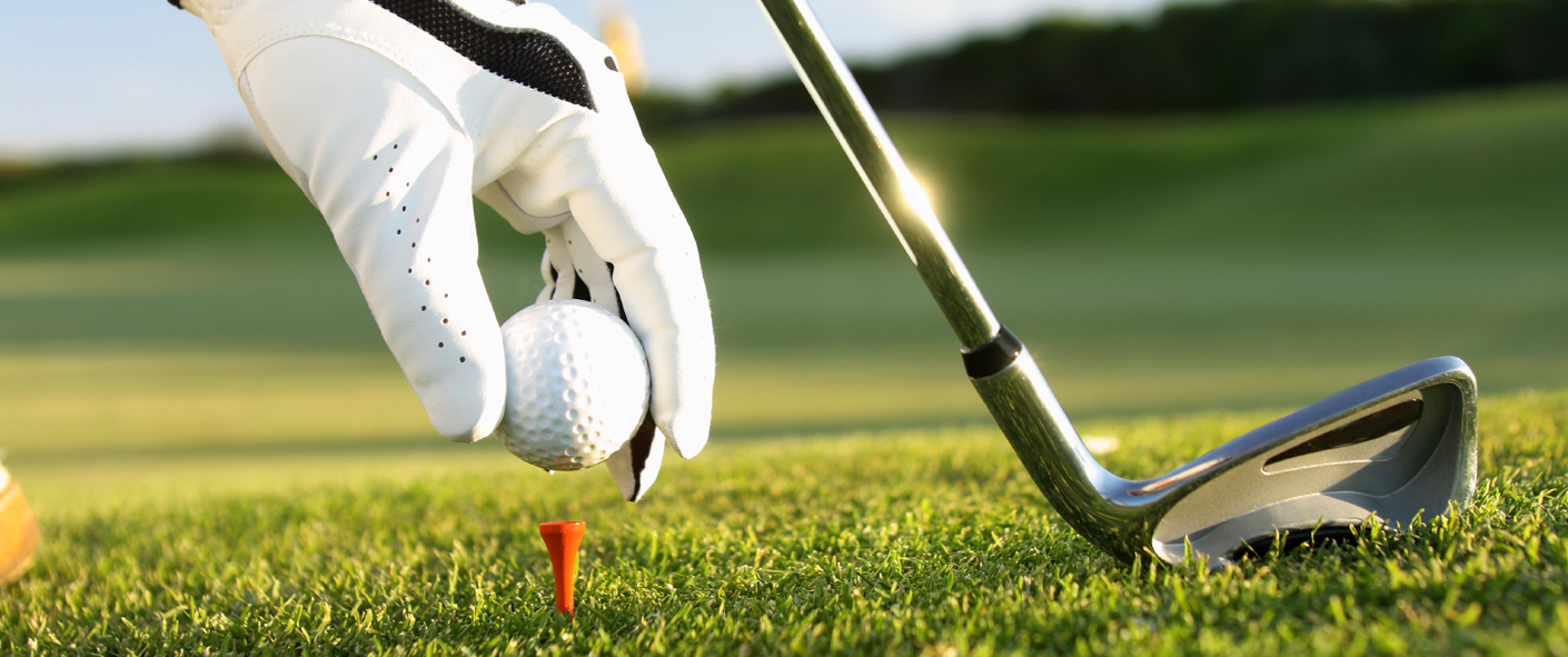 A golfer placing their ball on the tee