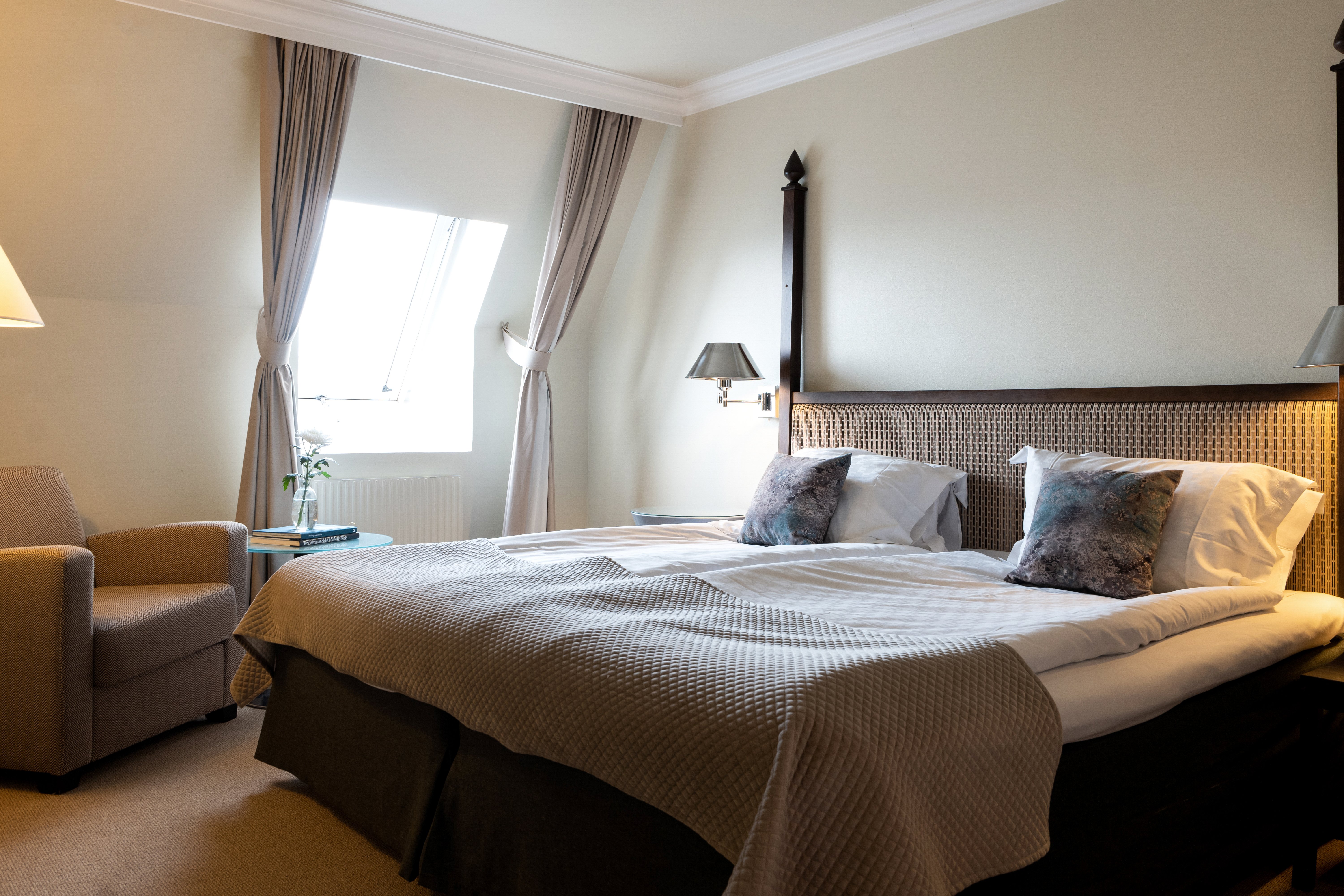 A hotel room with a double bed and armchair