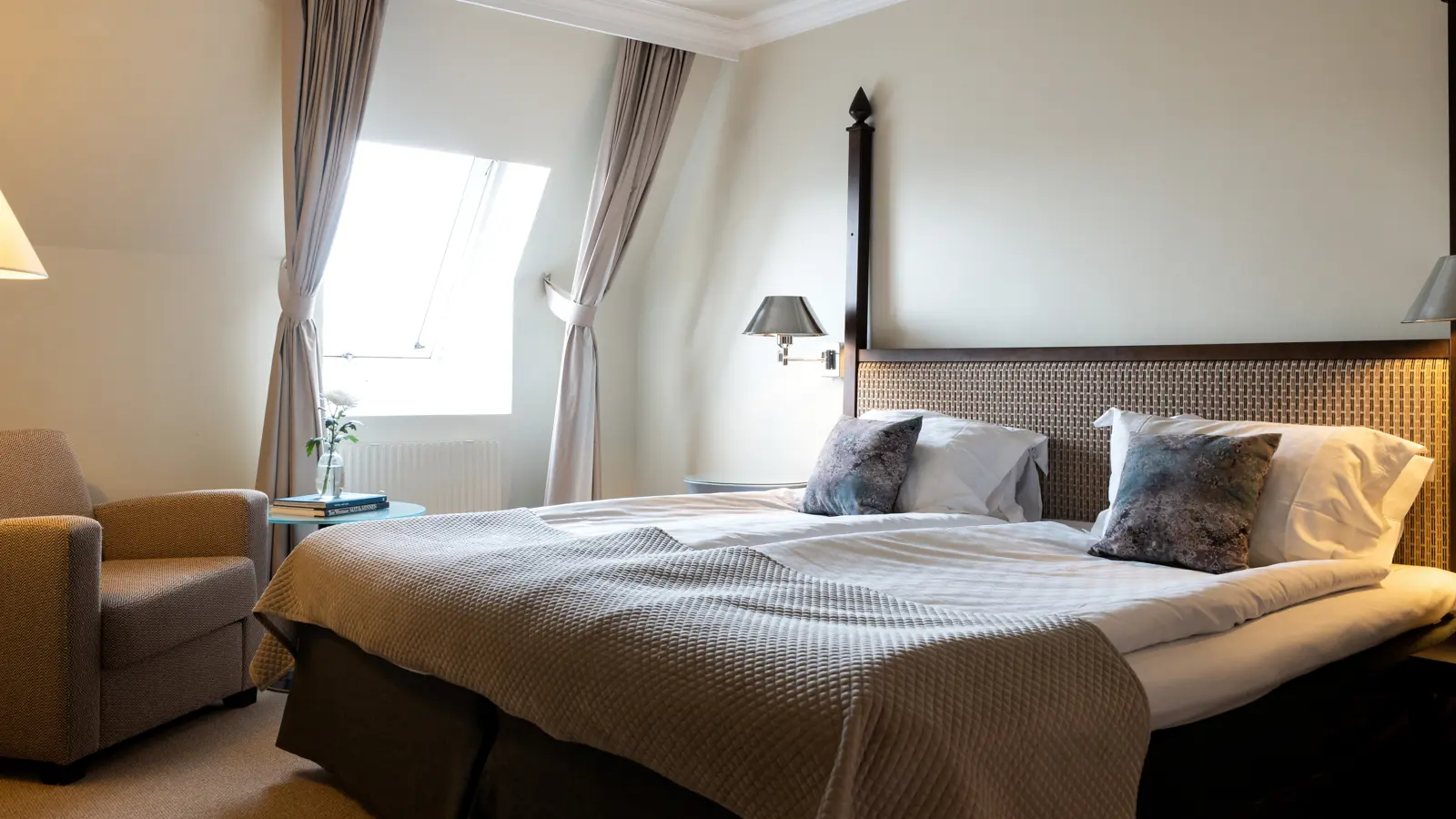 Ett hotellrum med dubbelsäng och fåtölj
