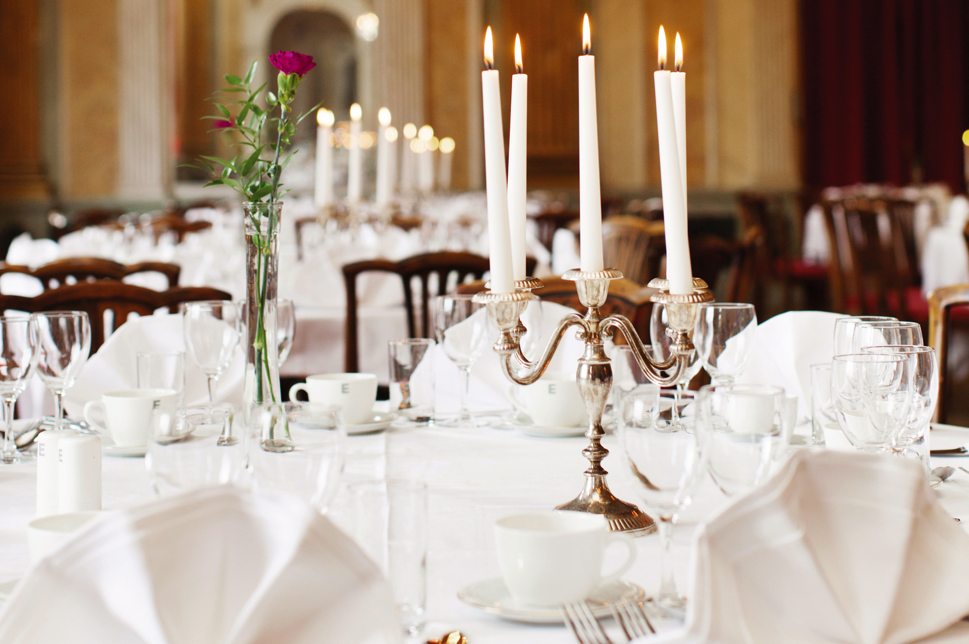 Uppdukade bord med vita dukar och tända ljus