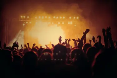 Publik på konsert lyfter händerna i luften mot en upplyst scen