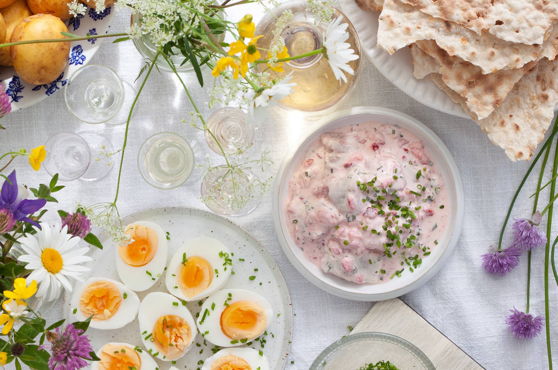 Matbord med midsommar dukning, mat och blommor