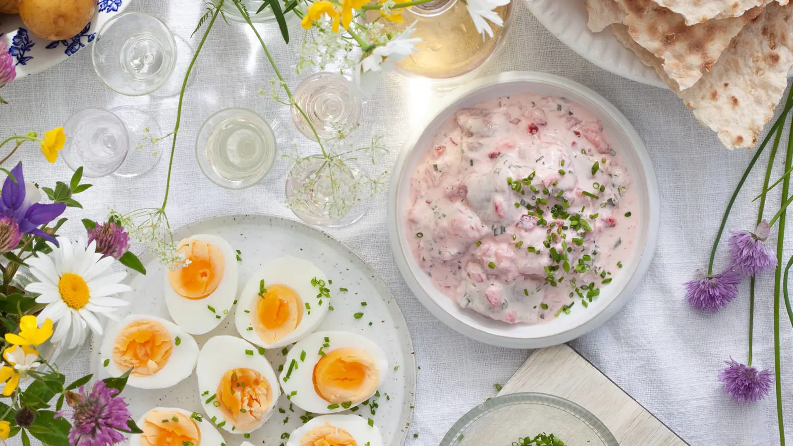 Matbord med midsommar dukning, mat och blommor