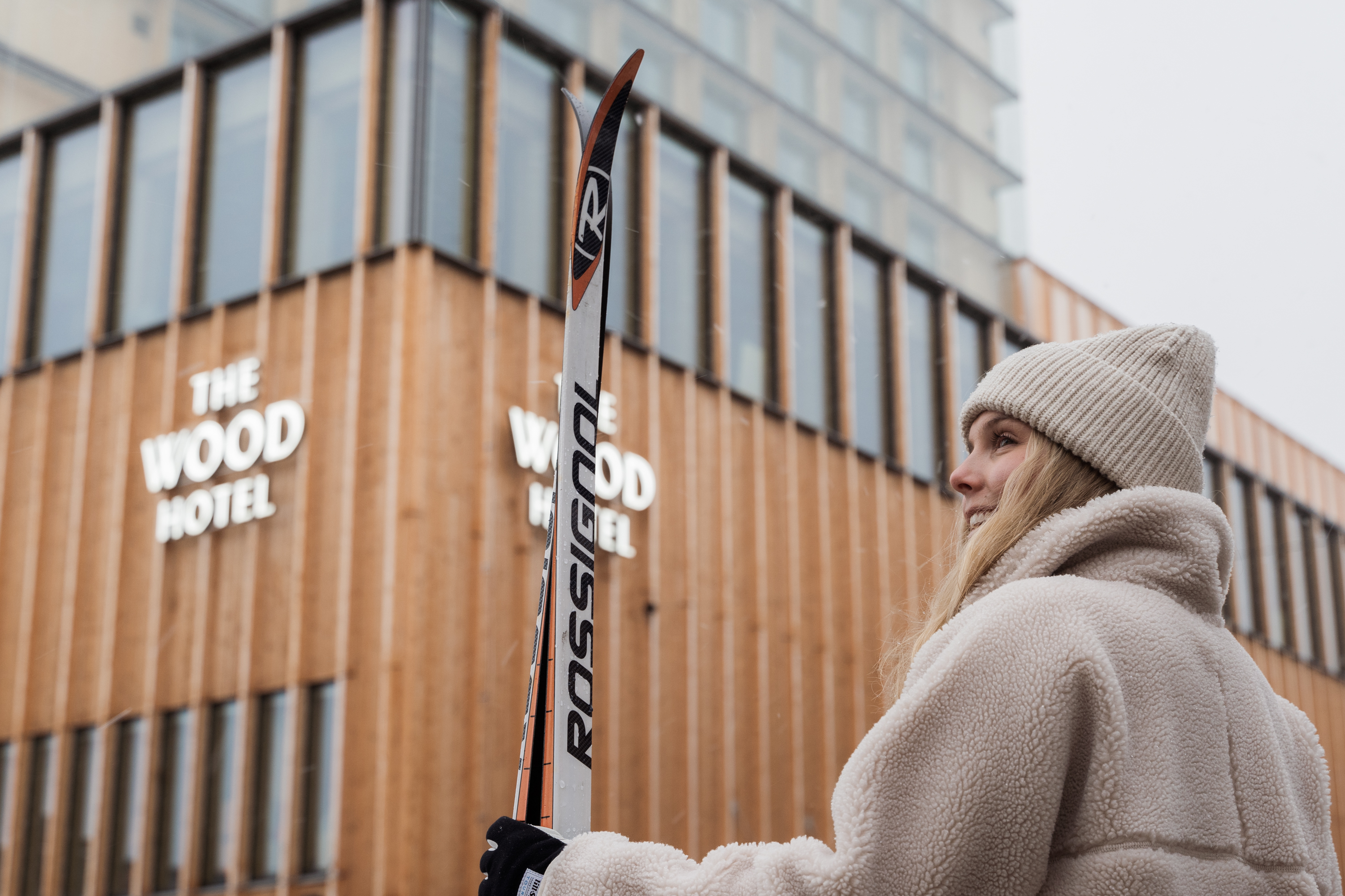 Skidåkare hållandes i ett par längdskidor som står framför The Wood Hotel by Elite