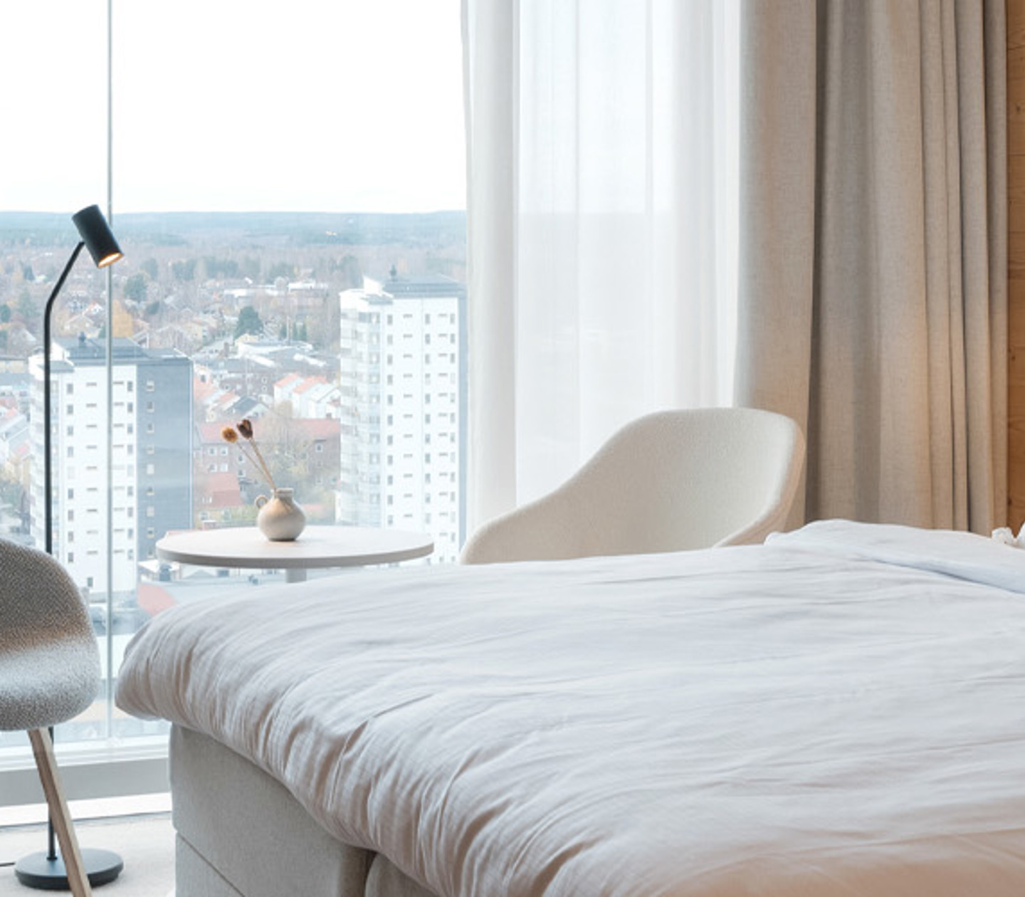 Cozy hotel room with double bed, TV, chairs and large windows overlooking Skellefteå