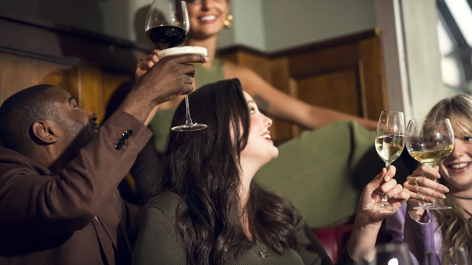 4 glada och festklädda människor skålar