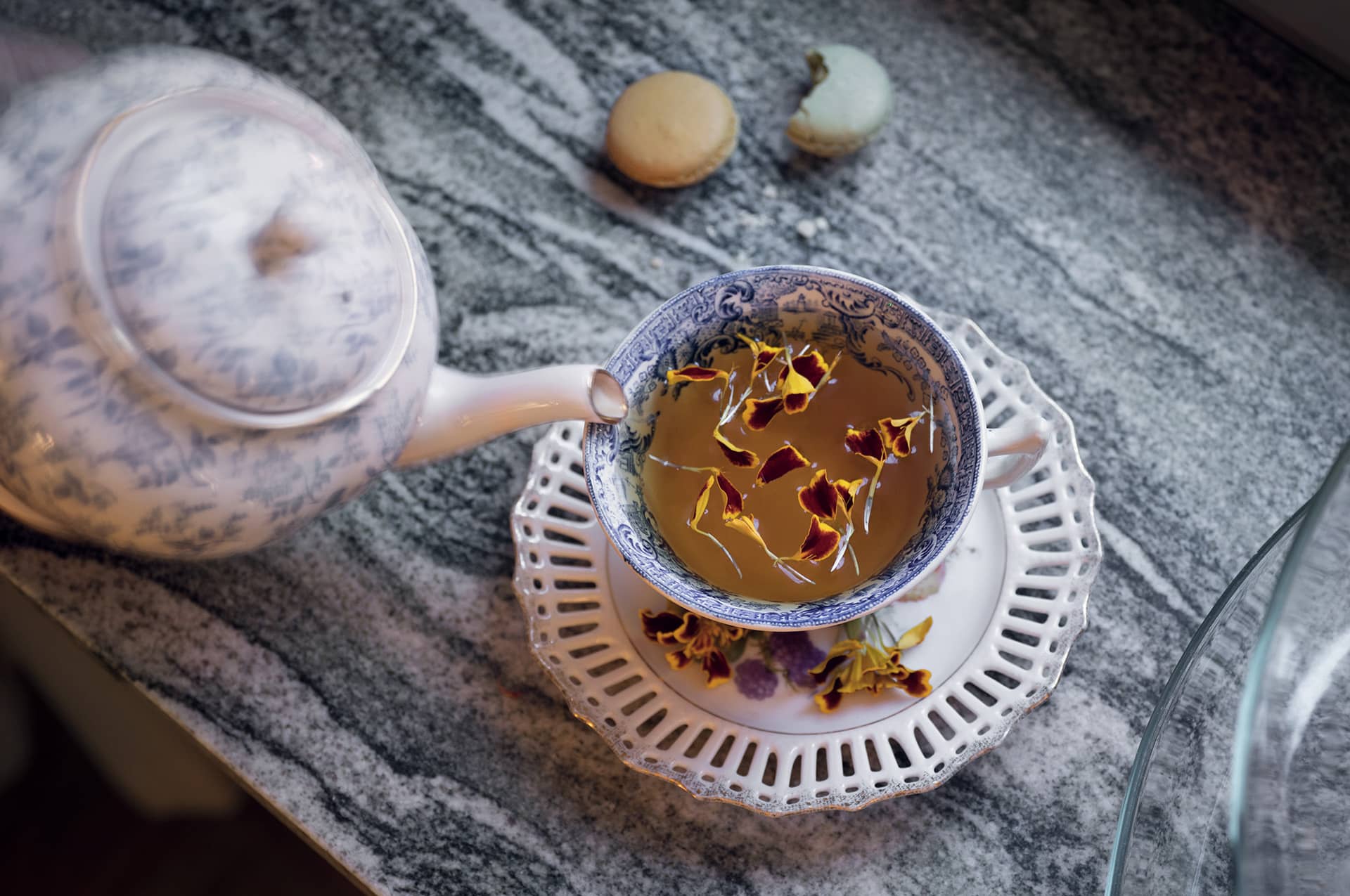 Tekanna som fyller tekopp med blomblad
