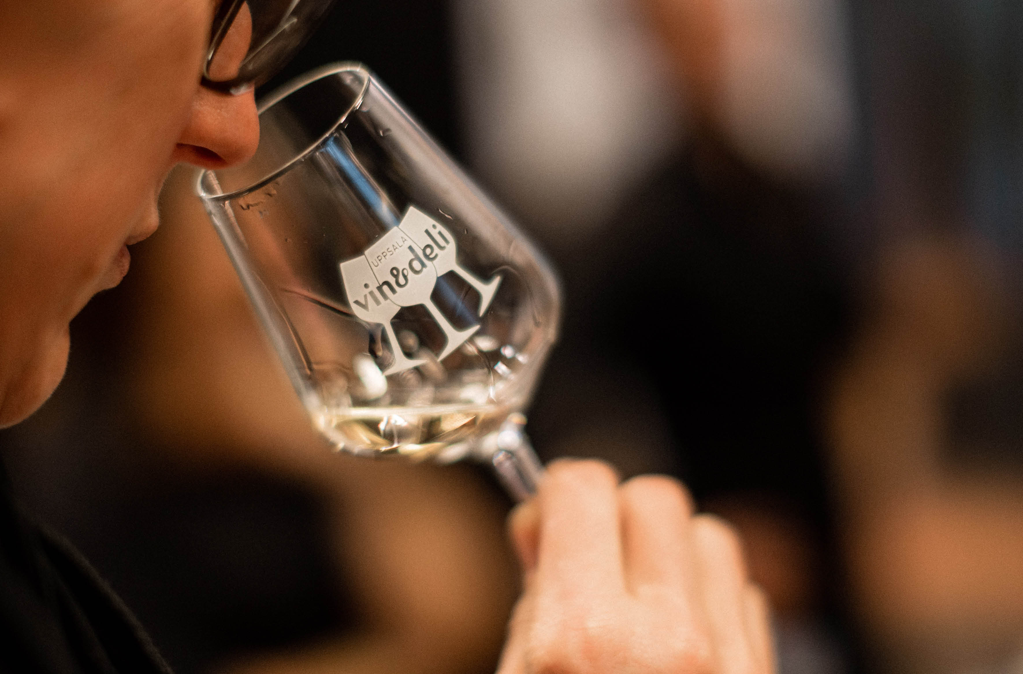 Person som doftar på vin ur ett vinglas