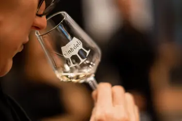 Person som doftar på vin ur ett vinglas