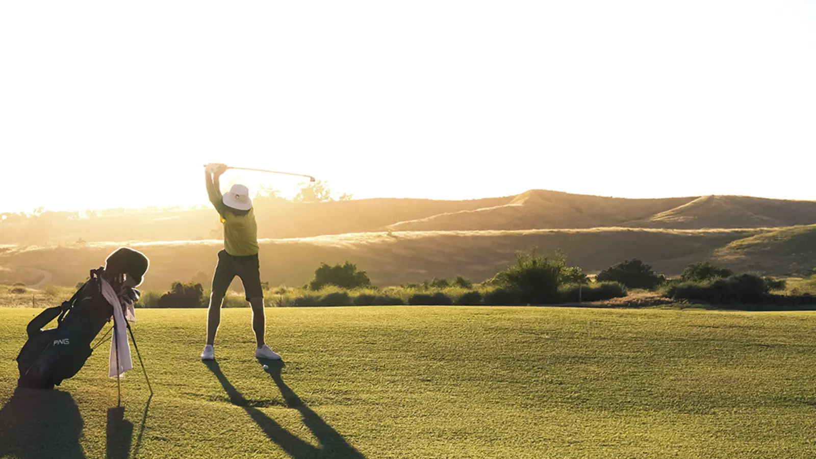 Woman in golf clothes lifts a club out of a bag