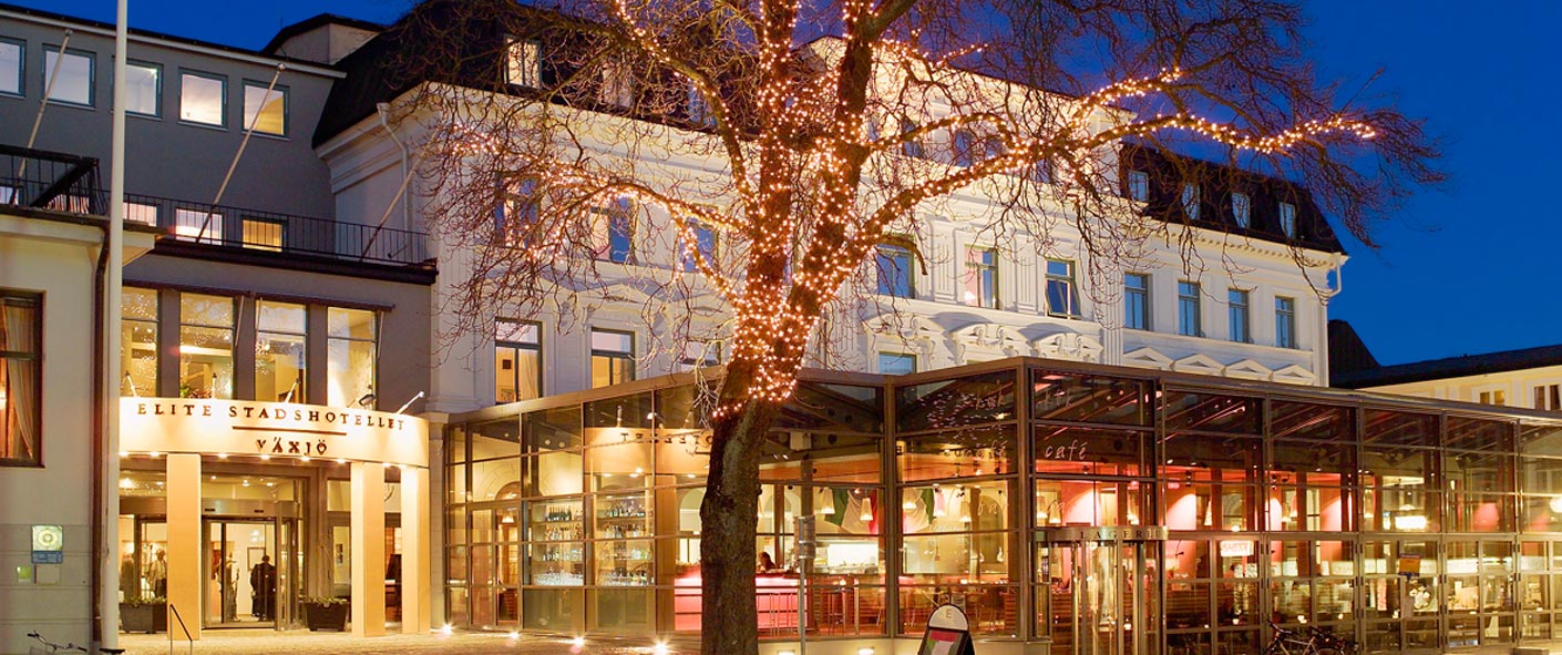 Pampig byggnad med stor uteservering i kvällsljus