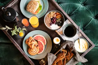 Frukostbricka med juice, kaffe, bröd och färsk frukt