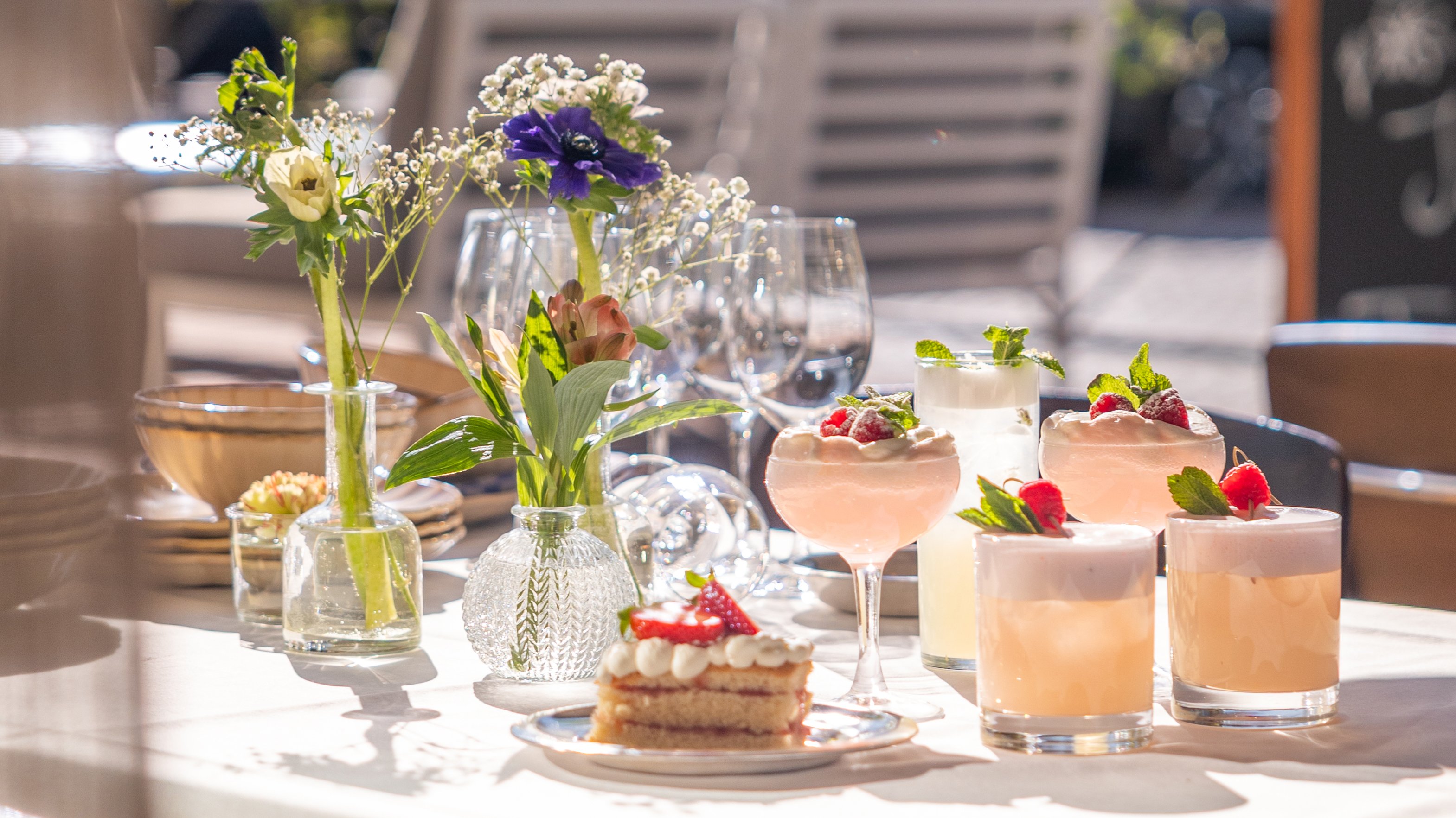 A summery table with flowers, cake and drinks