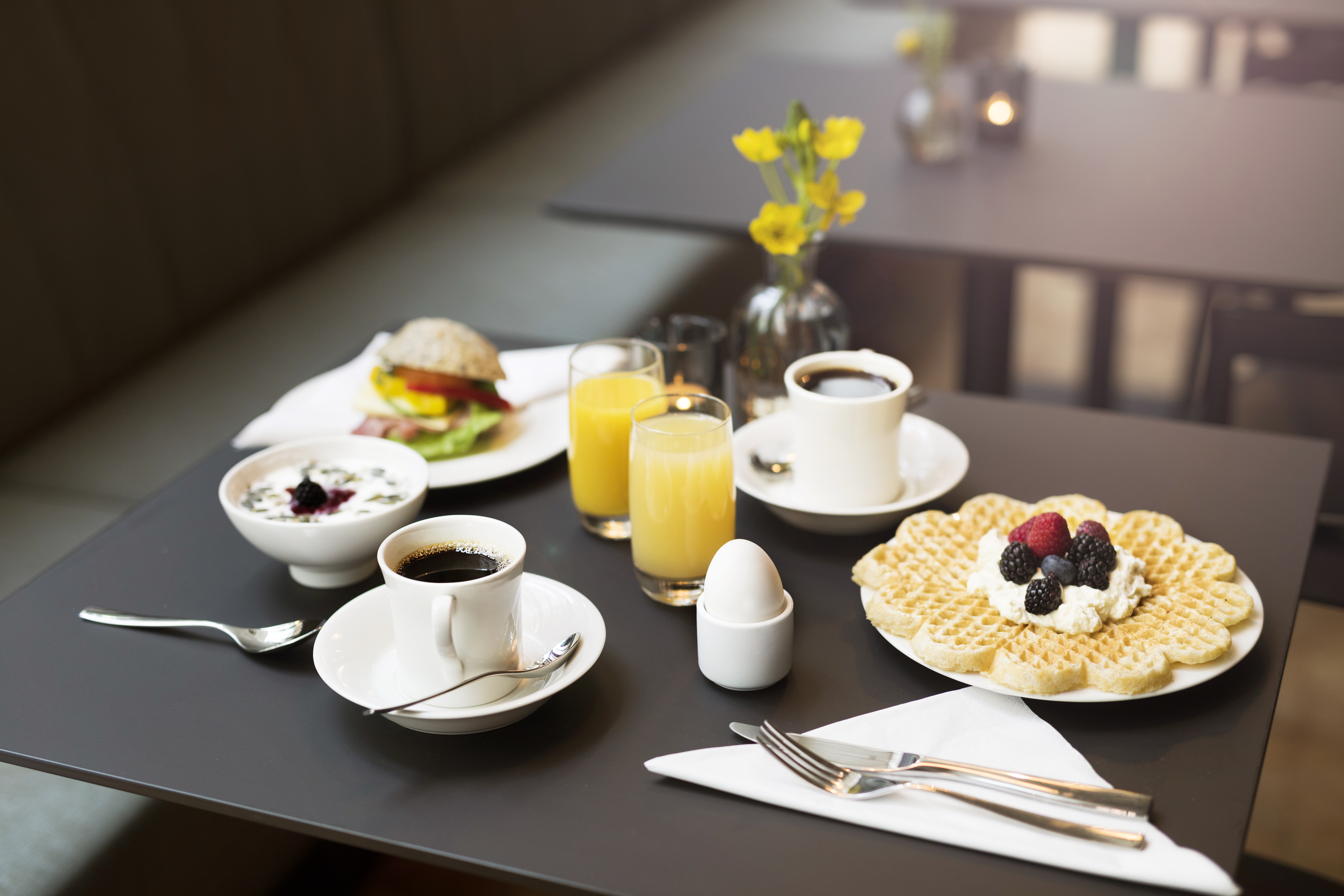 Breakfast laid out on the table with juice, coffee and waffles