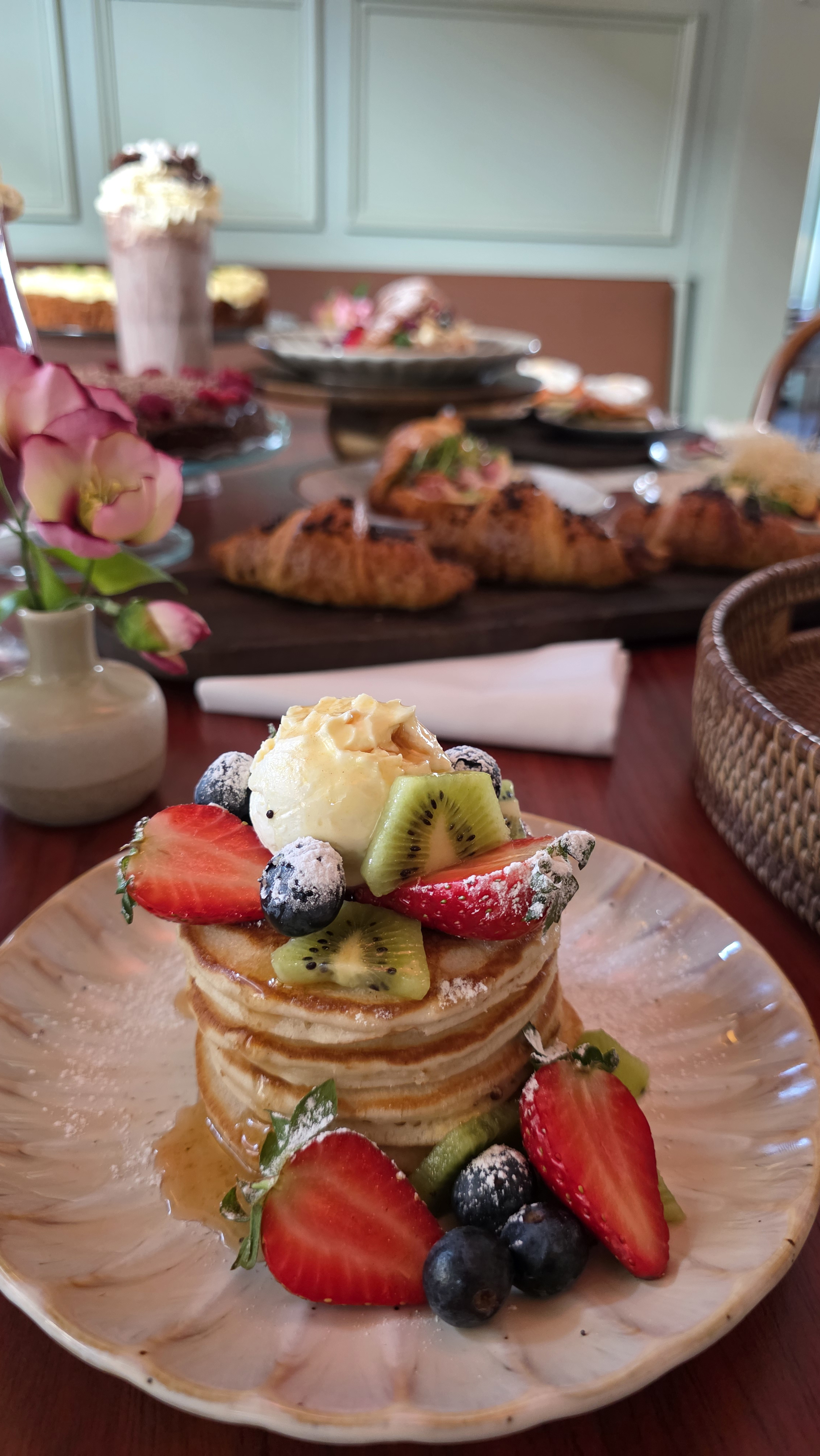 Pannkakor med frukt, bär och glass på ett cafébord.