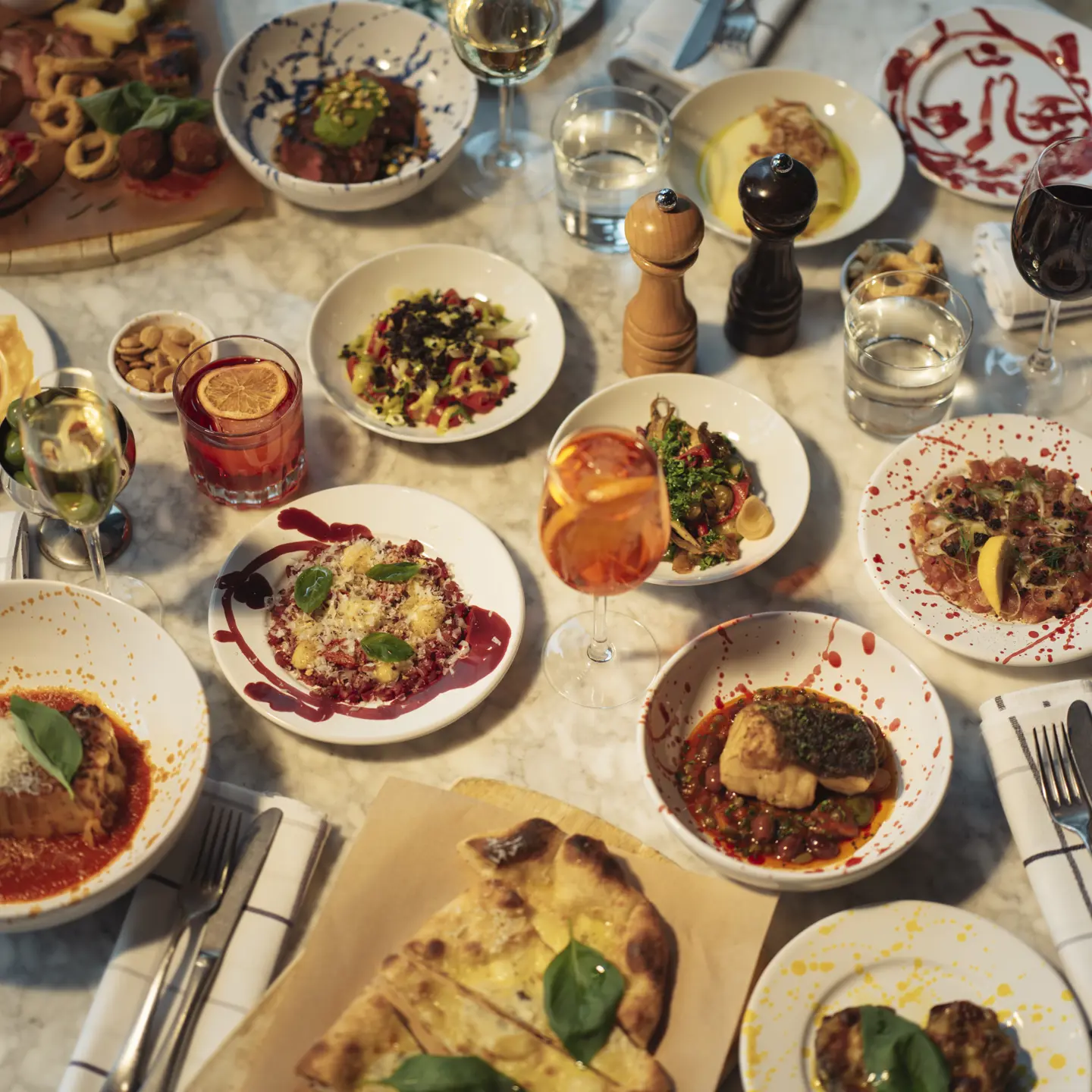 A pizza with ruccola and olives on the side