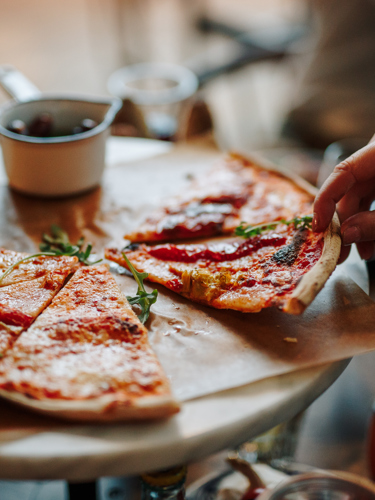 En pizza med ruccola på serverad med oliver