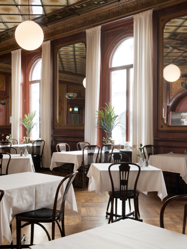 Nice dining room with mirrors on the walls and ceiling with large windows, many tables and chairs with white tablecloths