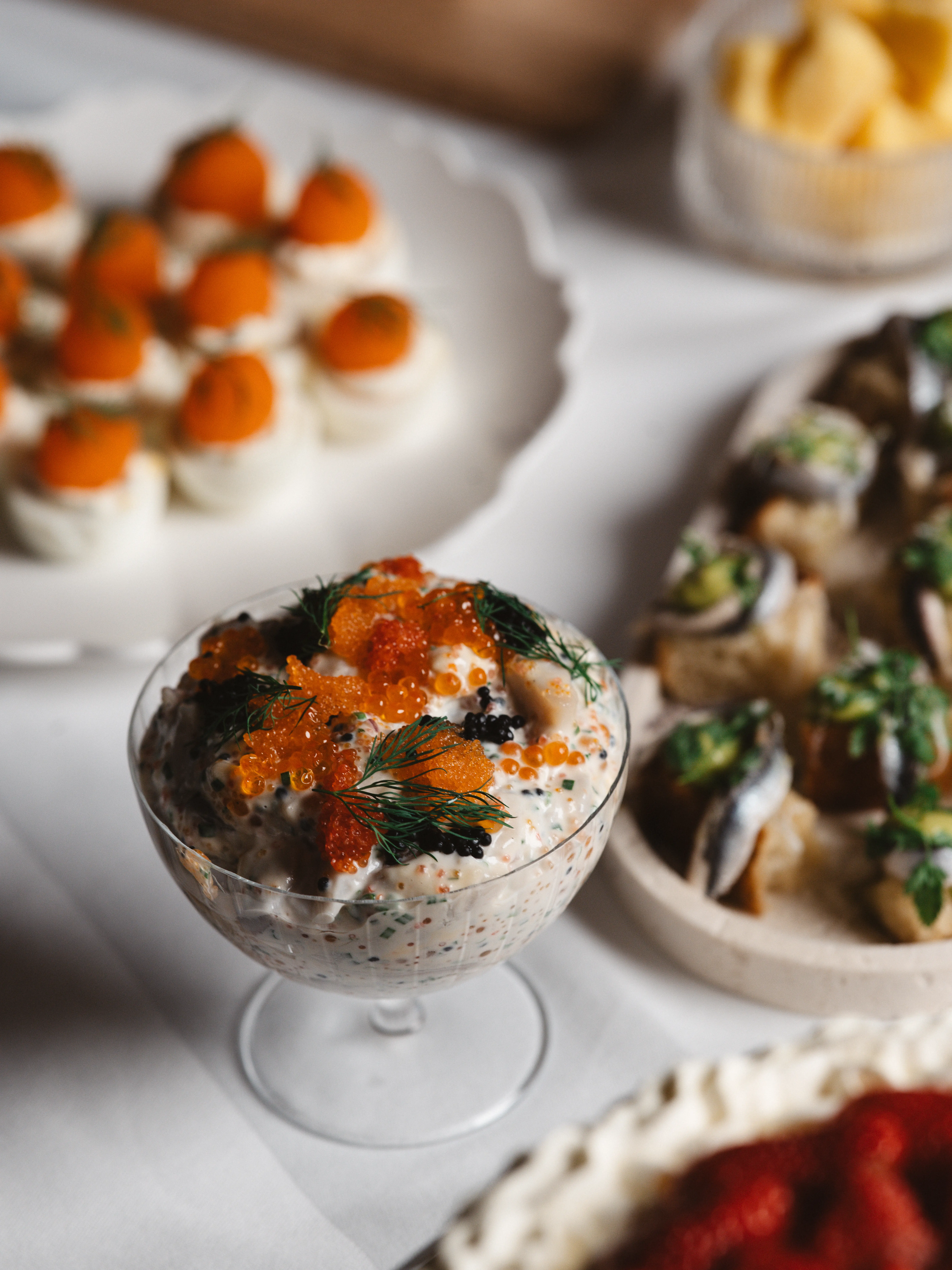 Klassisk svensk mat med löjrom, inlagd fisk och ägg på dukat bord.