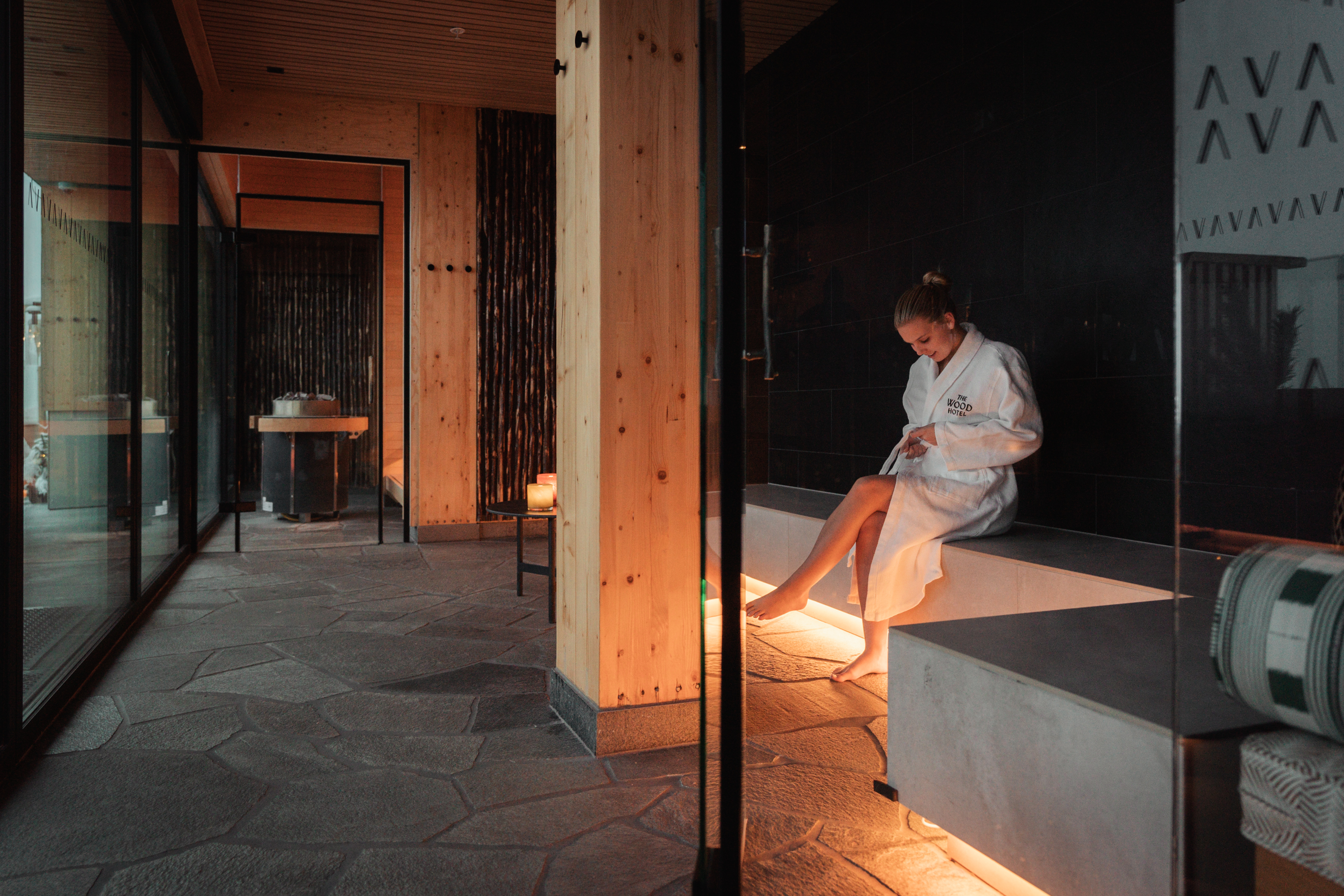 A woman sitting on a bed in a hotel room with wooden interior