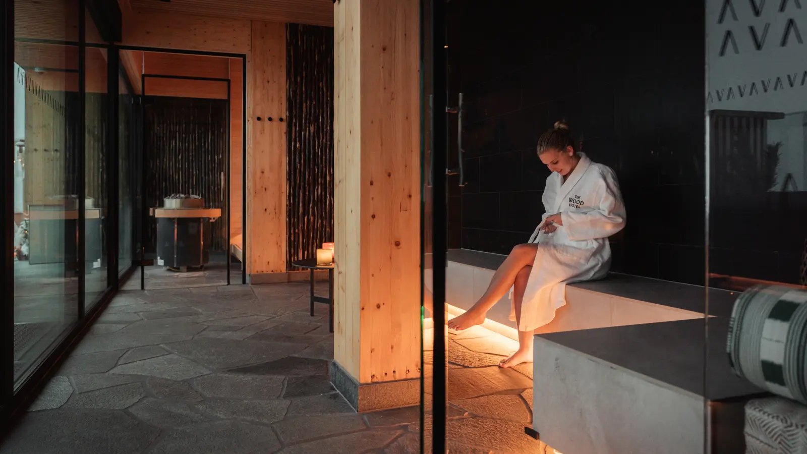 A woman sitting on a bed in a hotel room with wooden interior