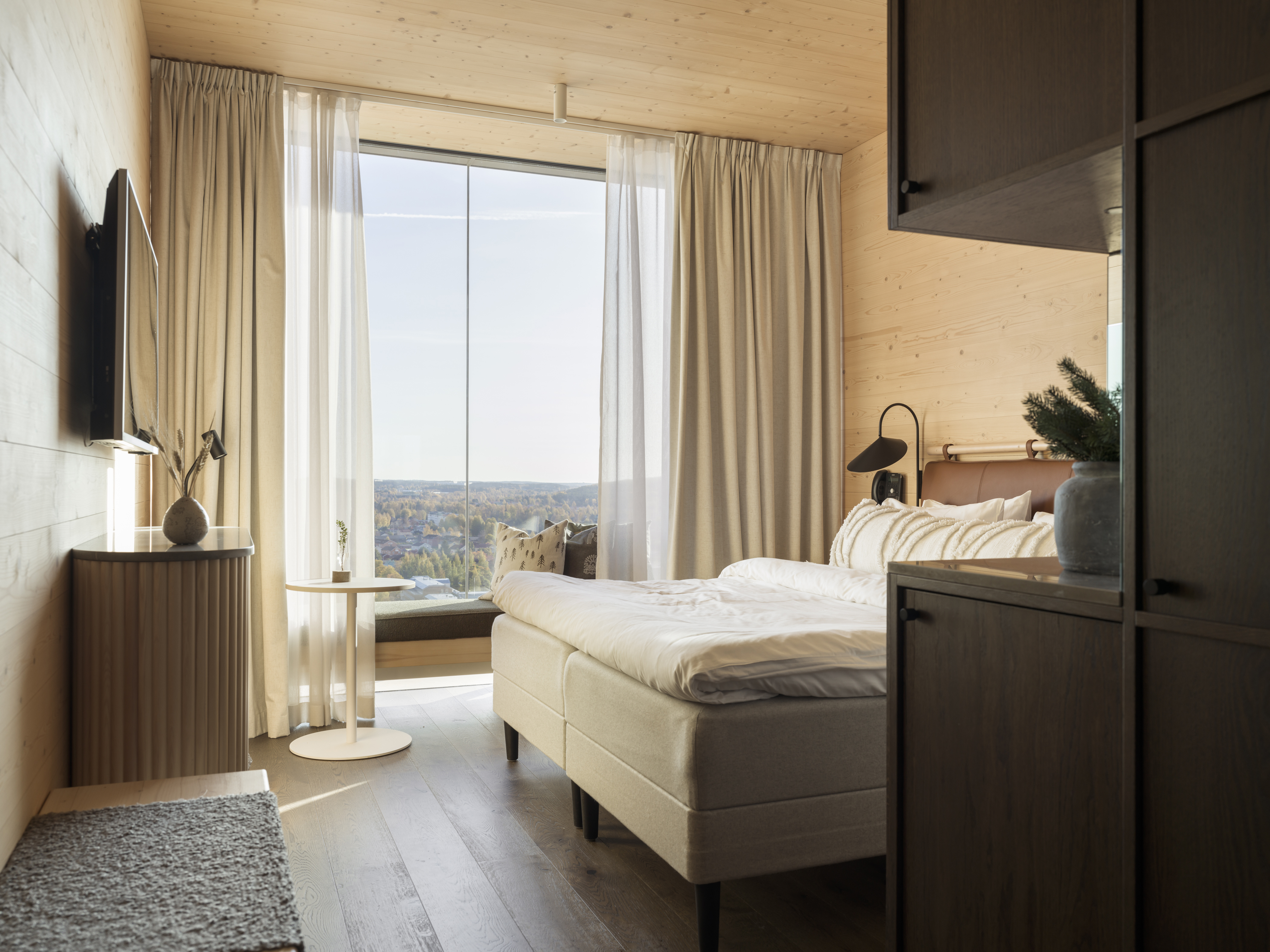 Modern Scandinavian bedroom interior with large window, natural wood walls, beige curtains, and minimalist furniture.