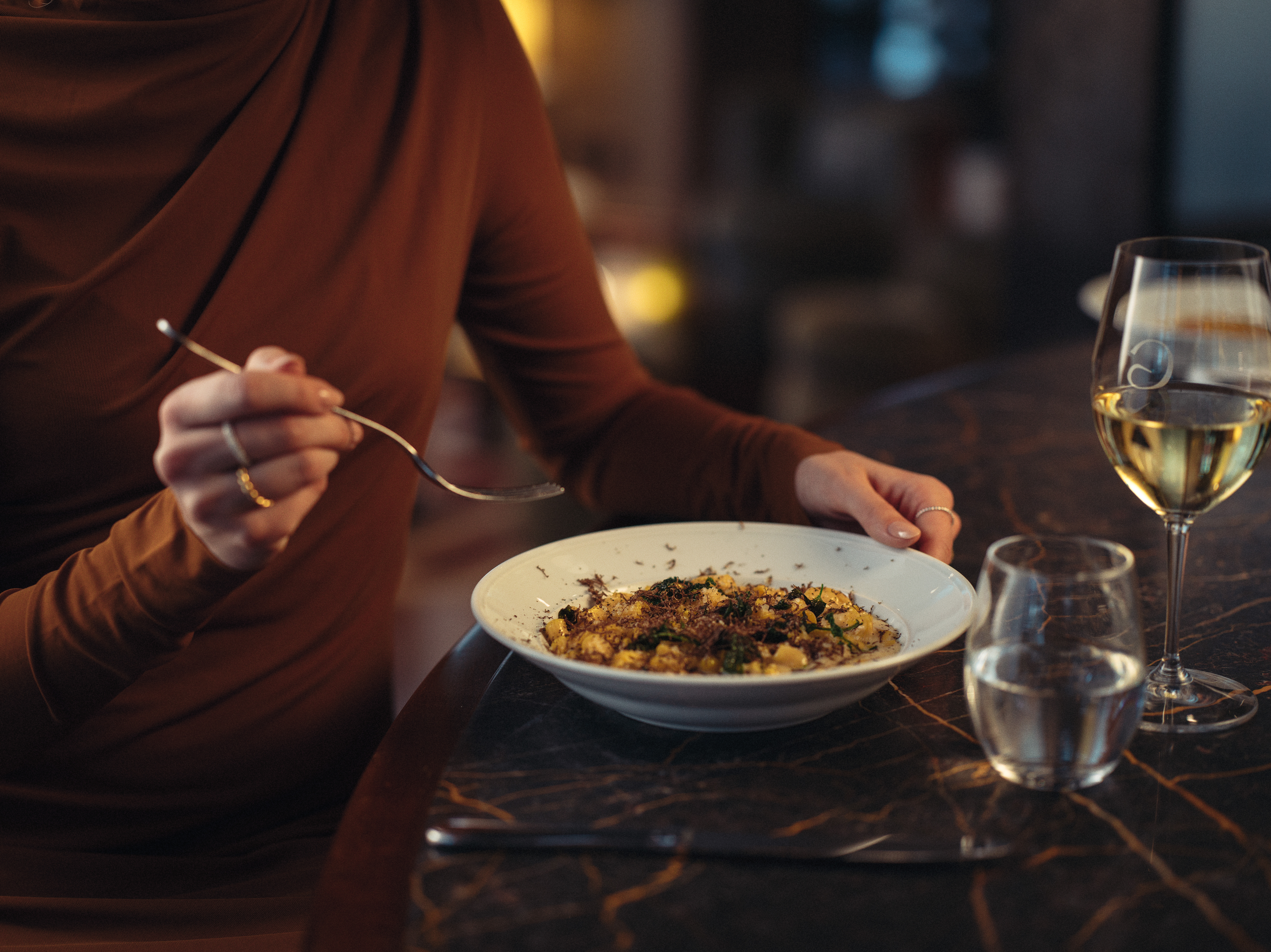 Woman with a plate of pasta and a glass of wine in front of her