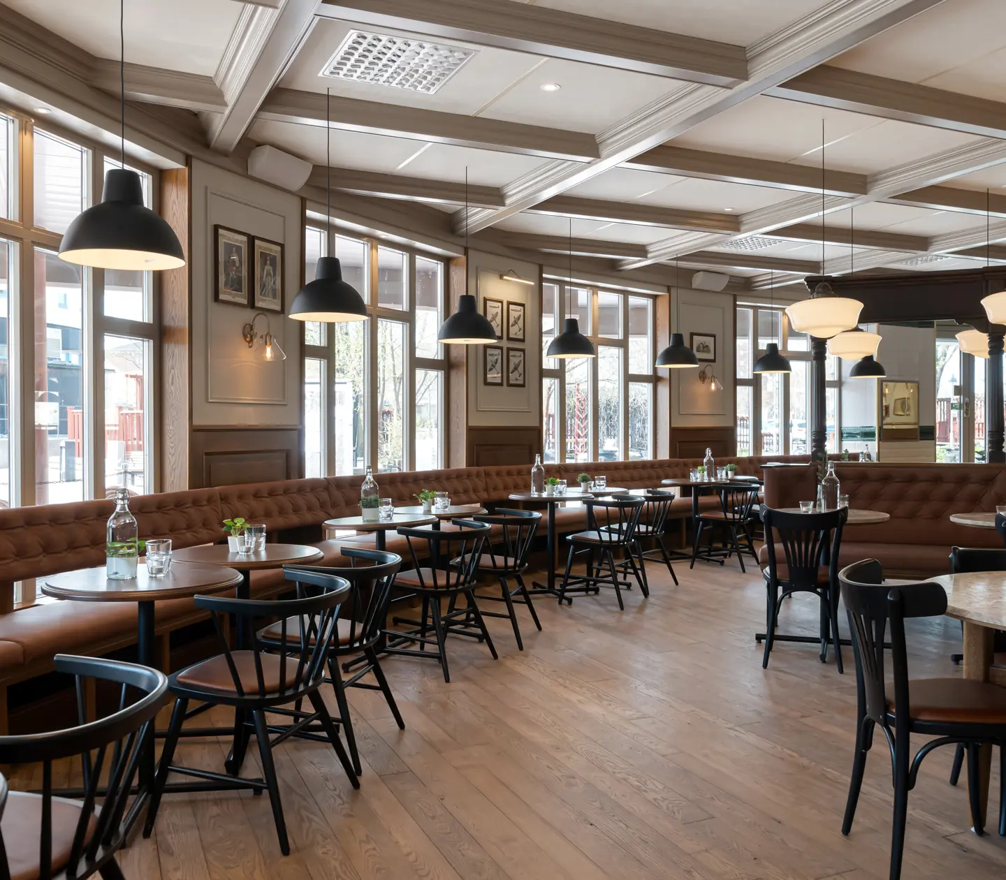 Restaurangmiljö med bord, taklampor och stora fönster