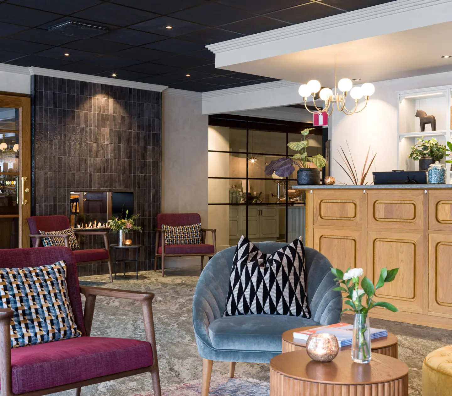 Mysig hotellobby med fåtöljer, brasa och växter