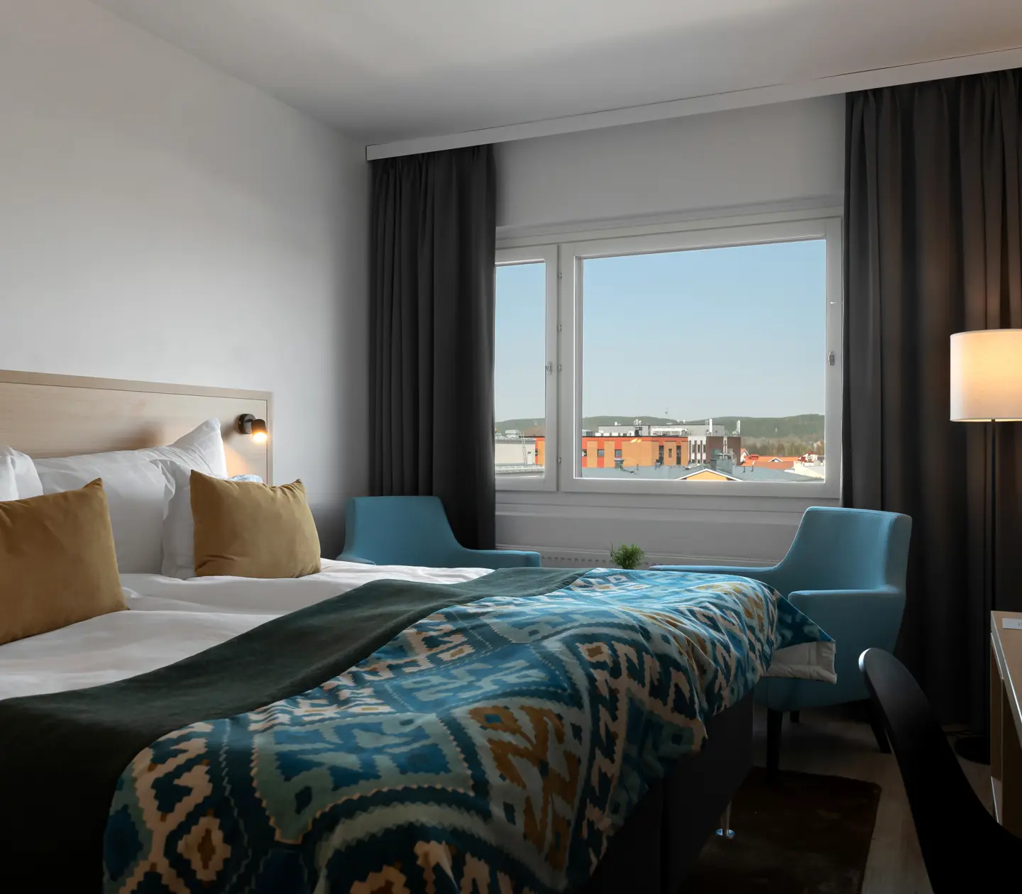 Hotellrum med dubbelsäng, skrivbord och fönster