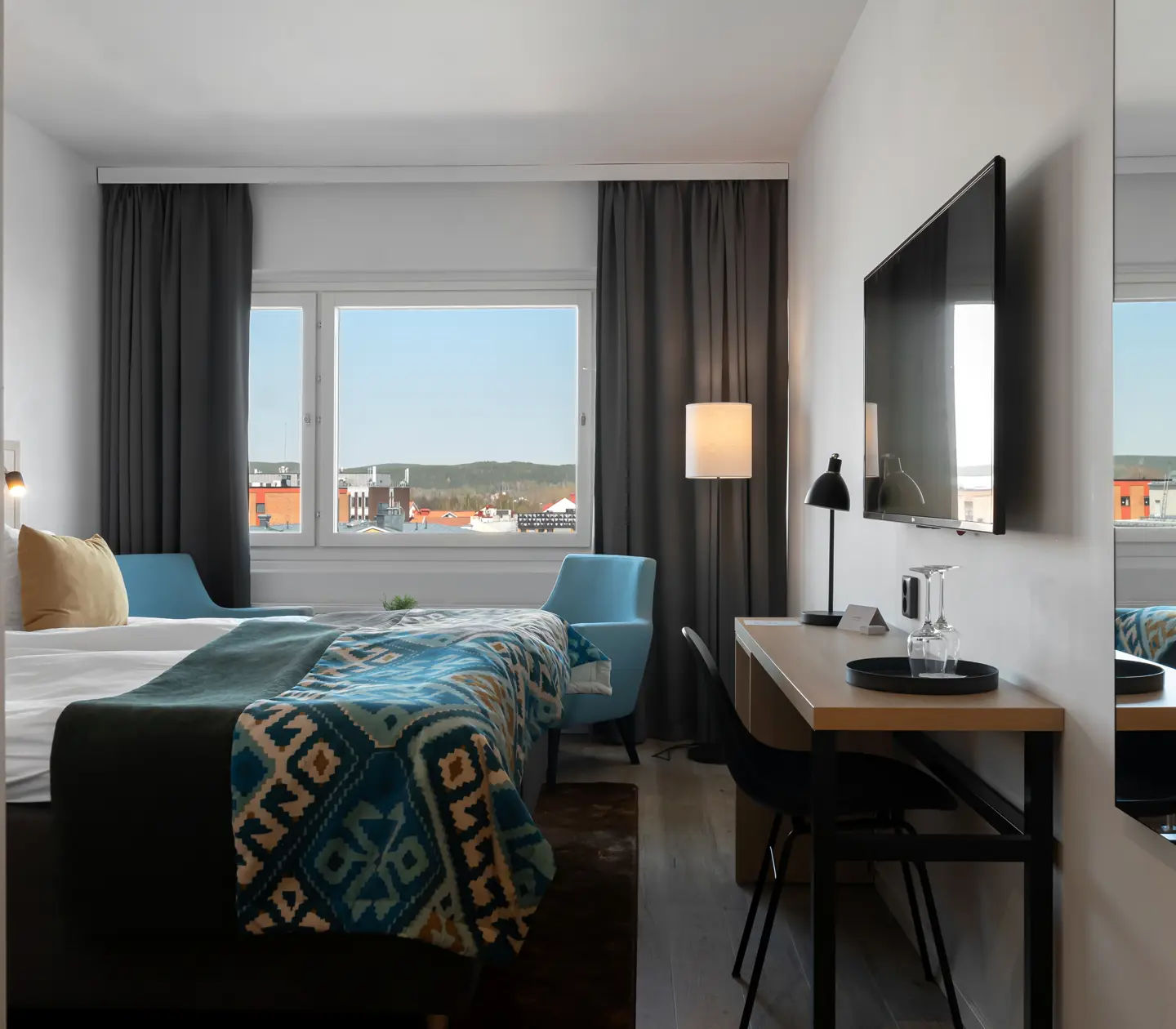 Hotellrum med dubbelsäng, skrivbord och fönster
