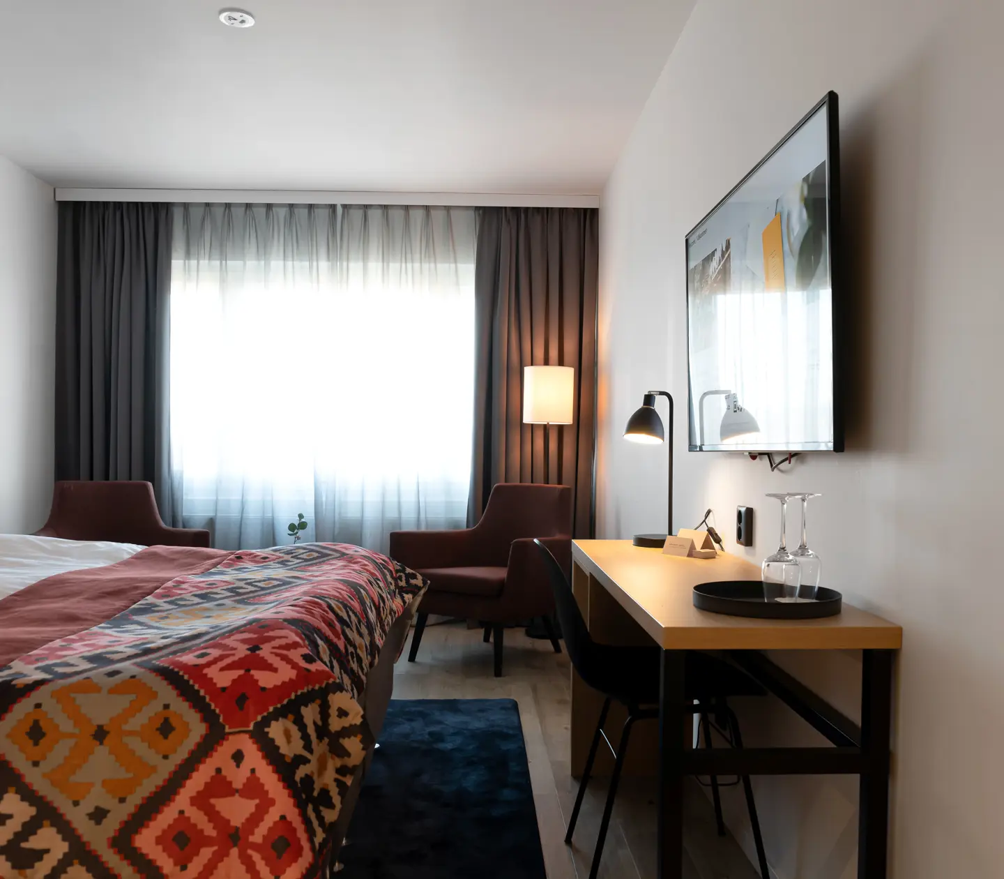 Mysigt hotellrum med dubbelsäng, fåtöljer och skrivbord