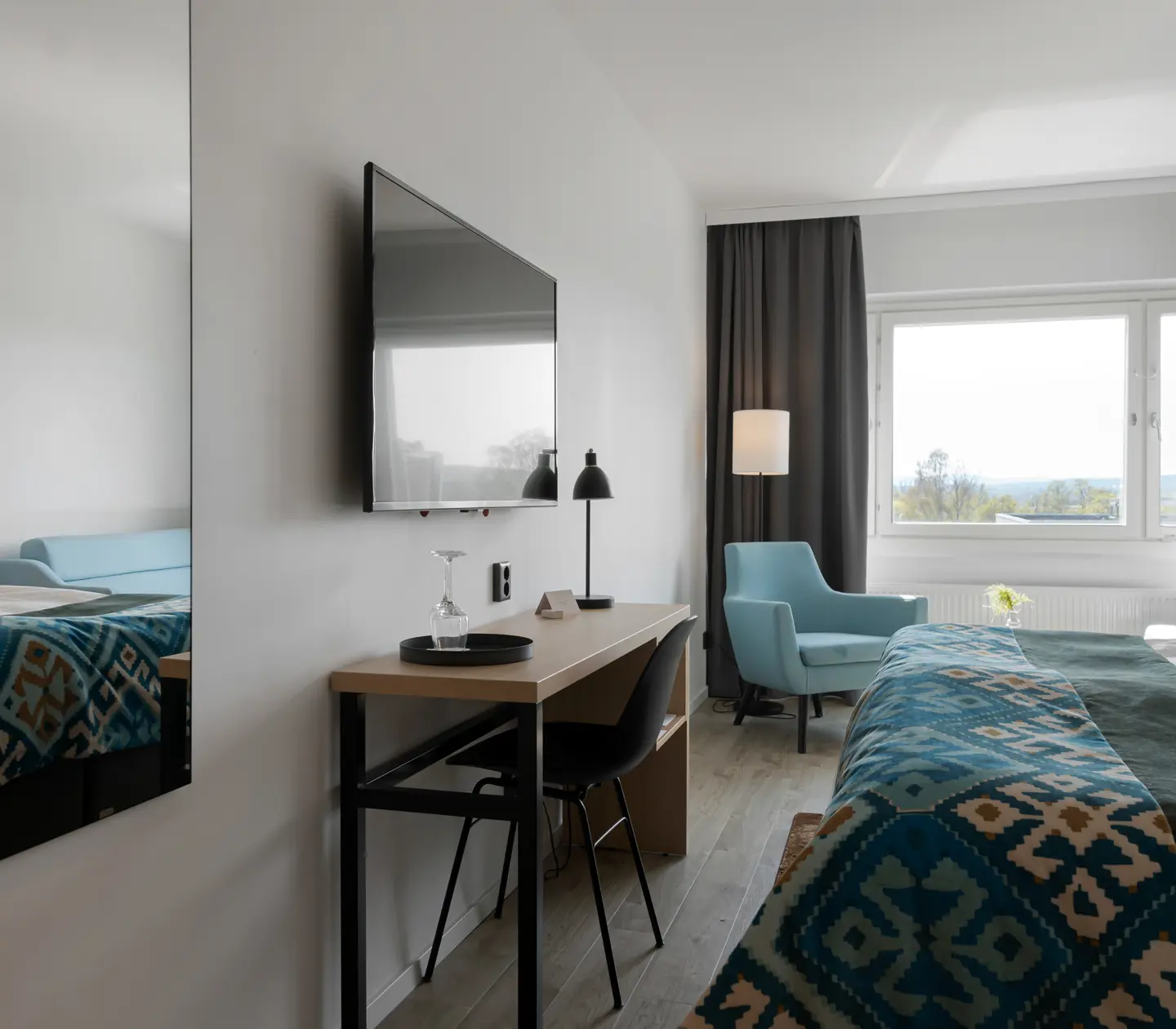 Hotellrum med dubbelsäng, skrivbord och fåtöljer
