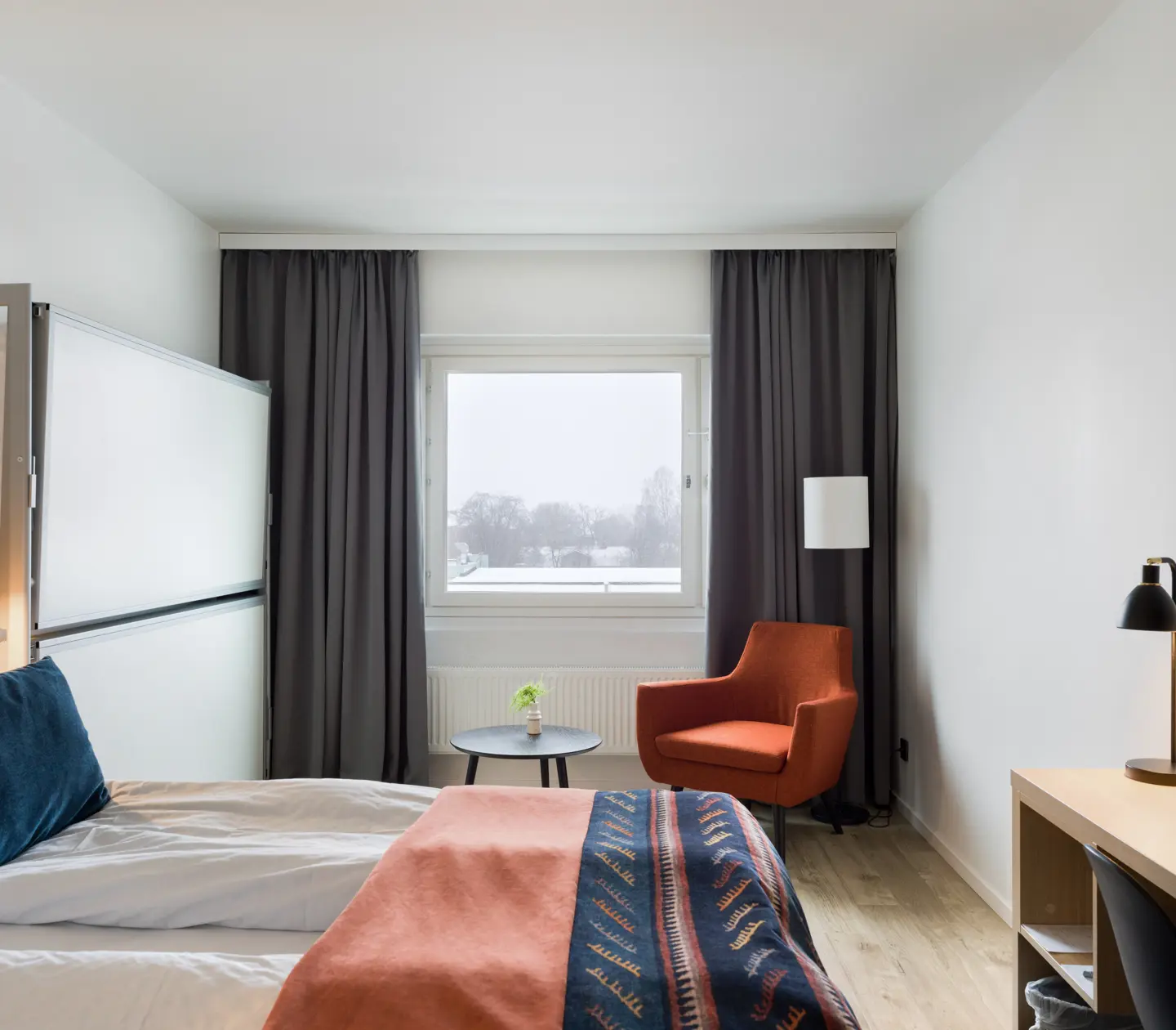 Hotellrum med dubbelsäng, uppfälld våningssäng och fåtölj