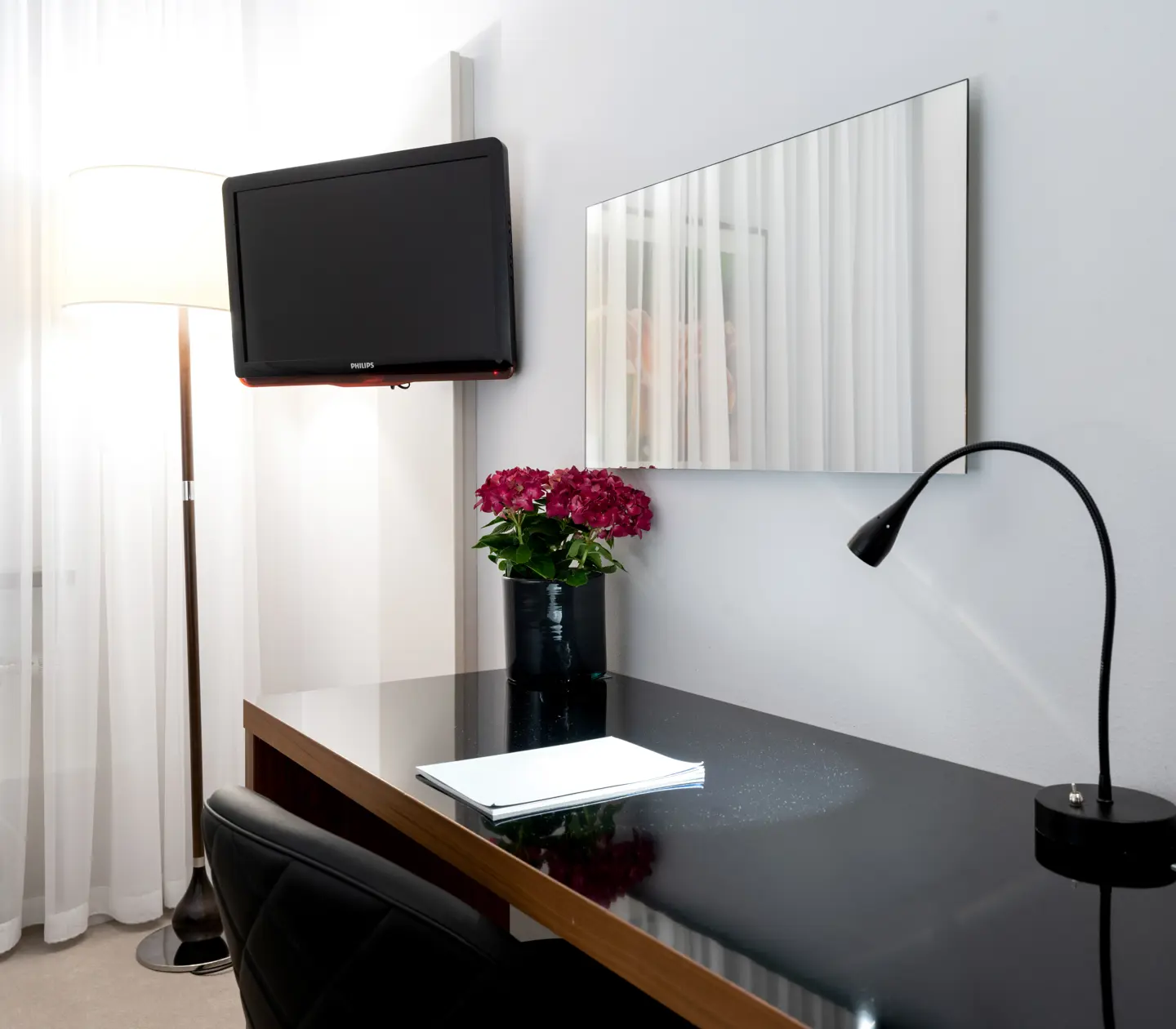 Hotellrum med skrivbord, spegel och tv